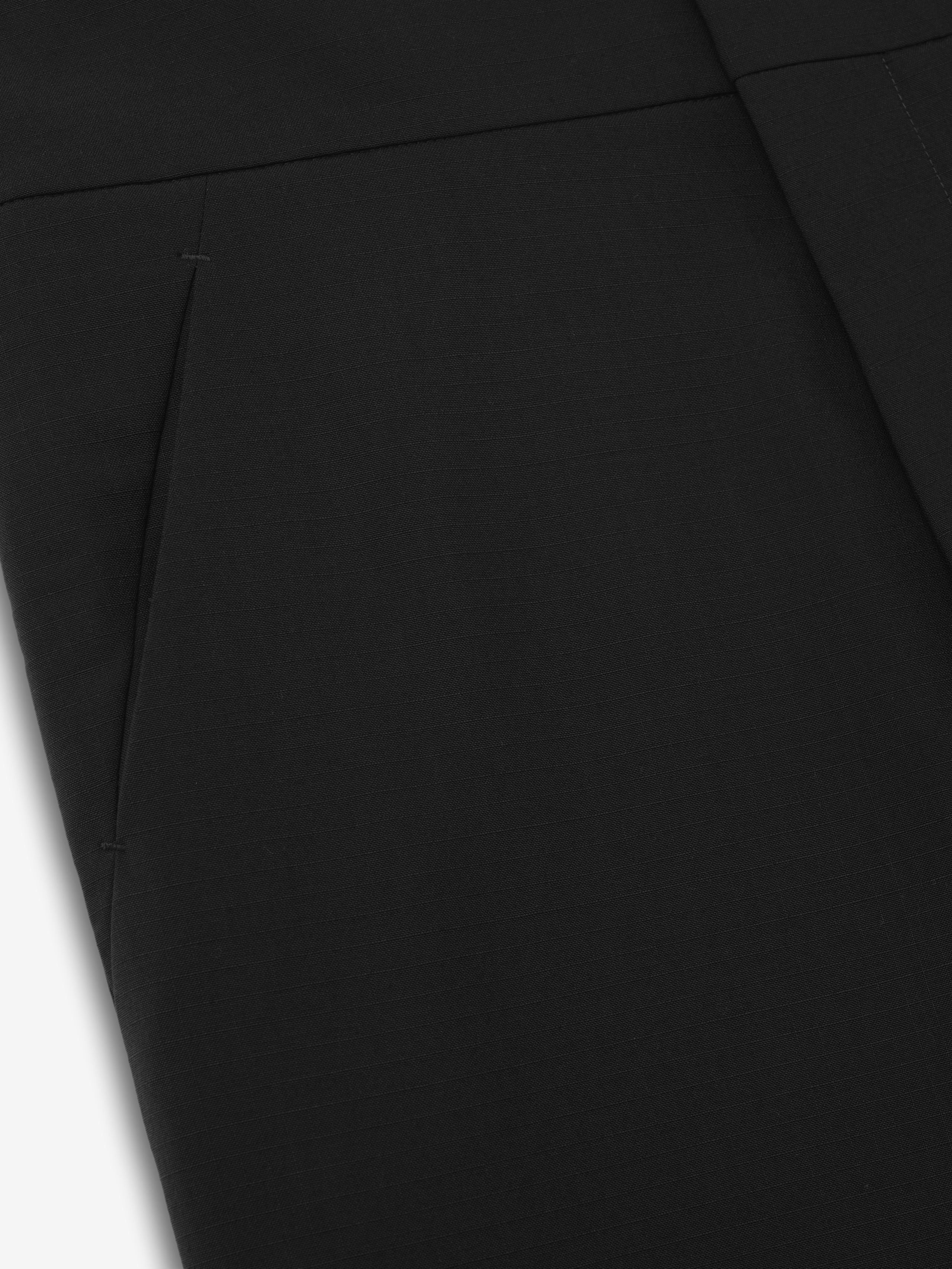 close-up of black ripstop virgin wool casual pants showing side seam pocket and flat front construction on smooth fabric