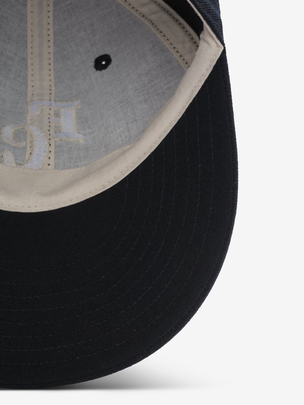 close-up of black wool baseball cap interior showing off-white sweatband and stitching details on brim and panels