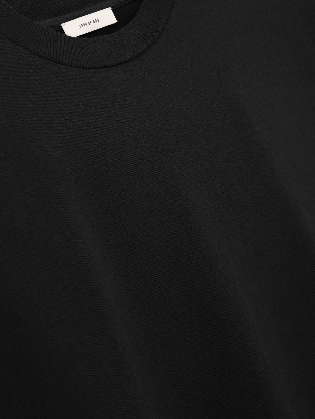 Close-up of a black short-sleeve shirt with a ribbed crew neckline and a white label inside the collar