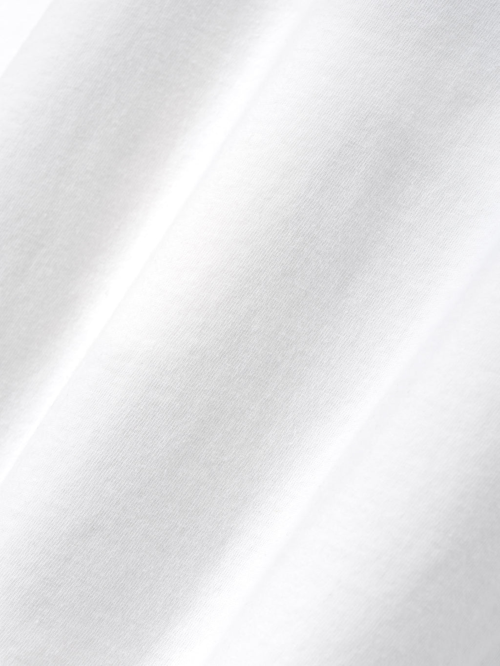 Close-up of soft white fabric with subtle folds and smooth cotton texture in natural lighting