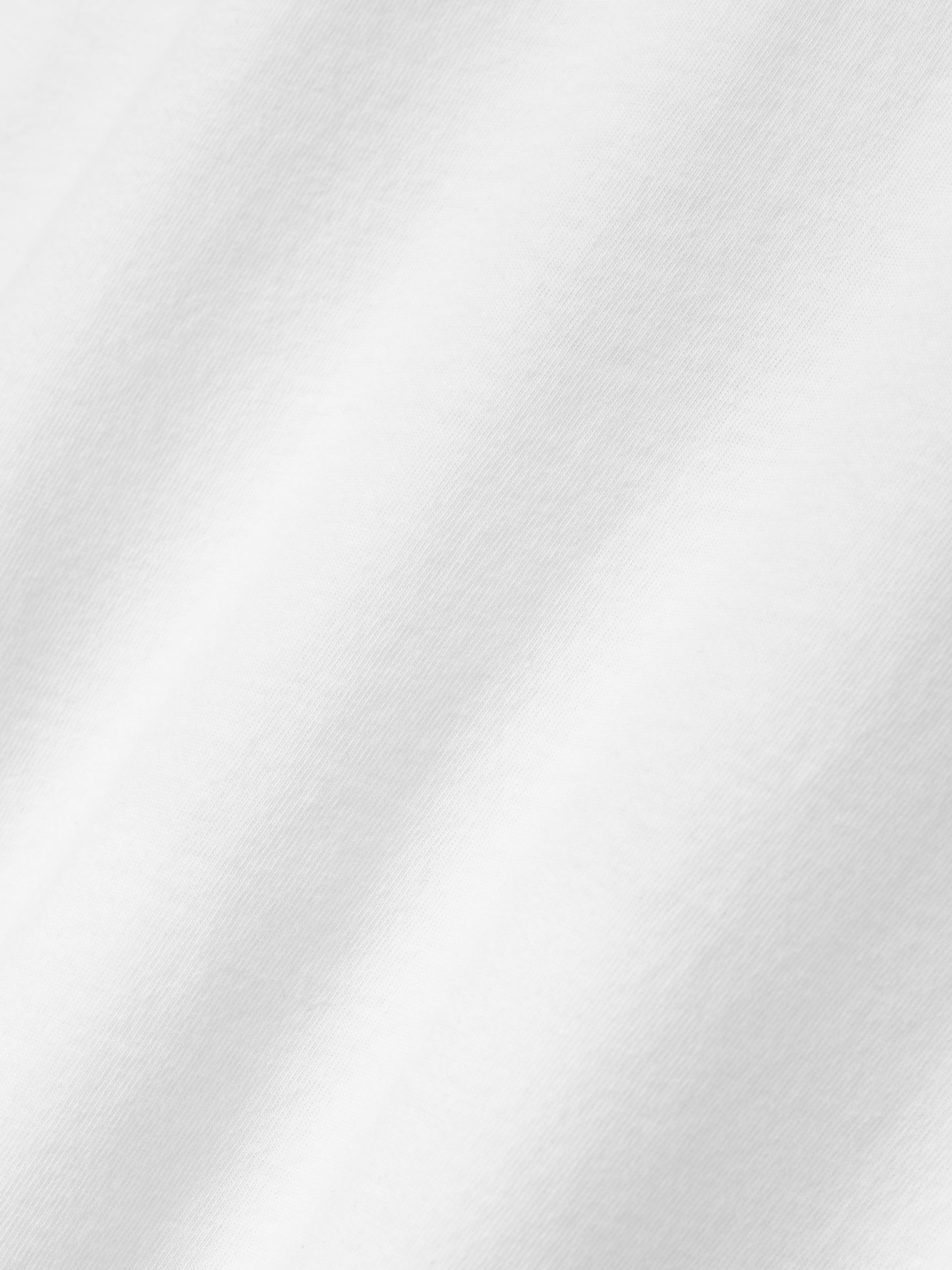 Close-up of smooth white fabric with subtle texture and soft folds visible on the surface