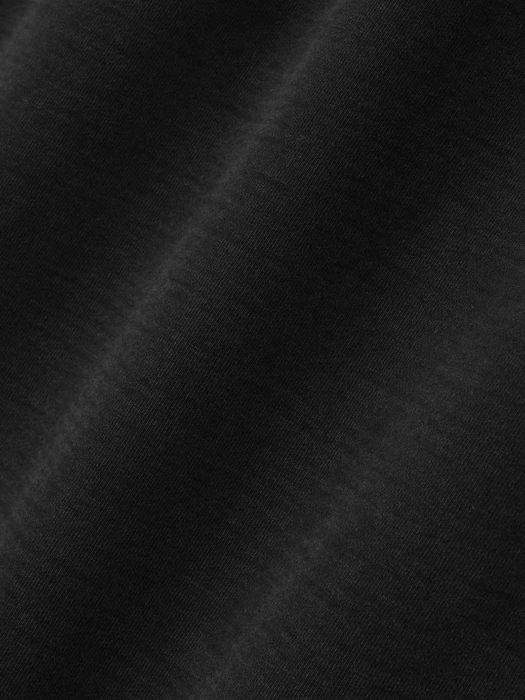 Close-up of smooth black fabric texture with soft folds and subtle sheen visible on surface