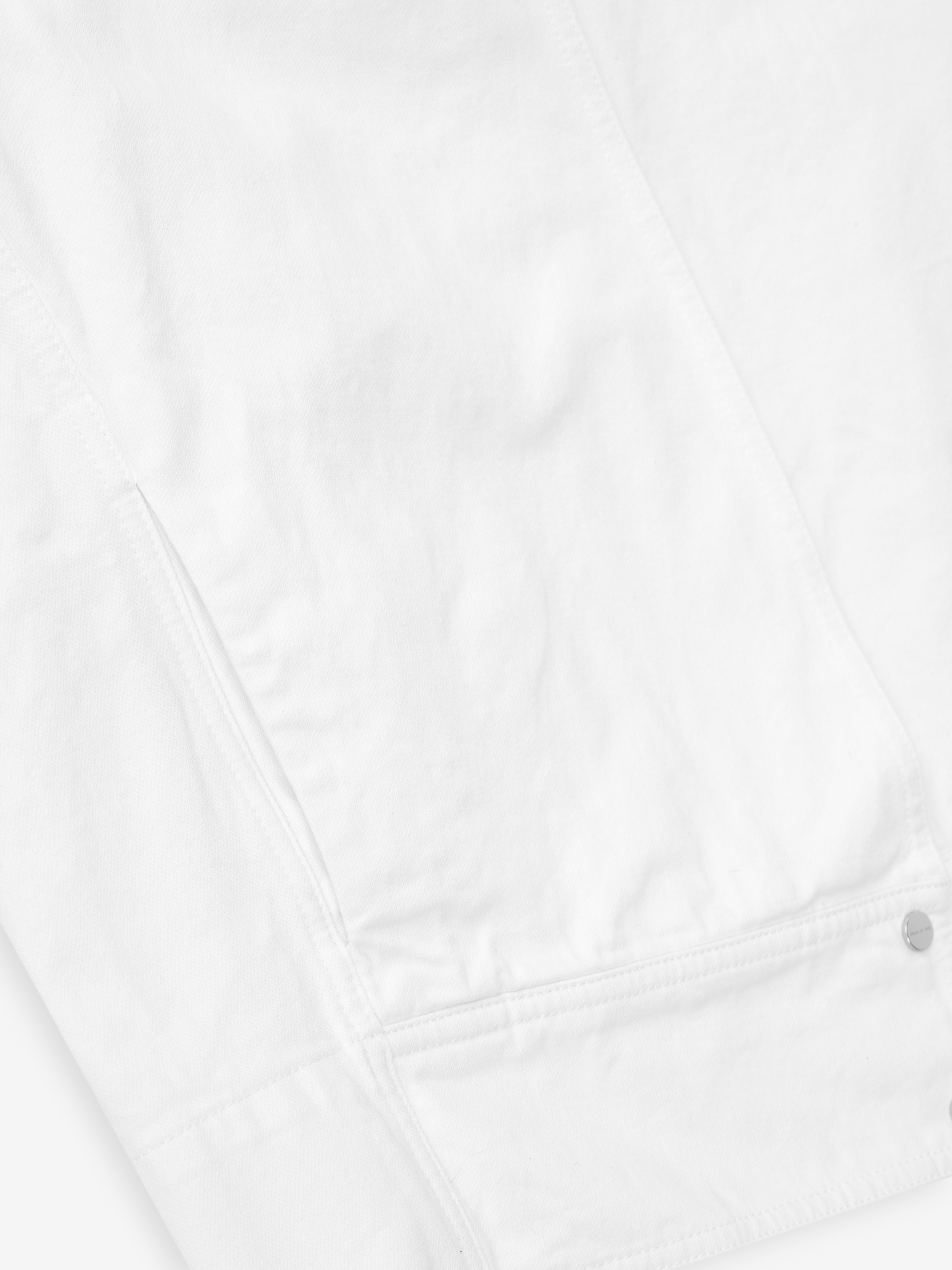 detailed view of optic white cotton broken twill fabric with snap button and pocket stitching on relaxed jacket