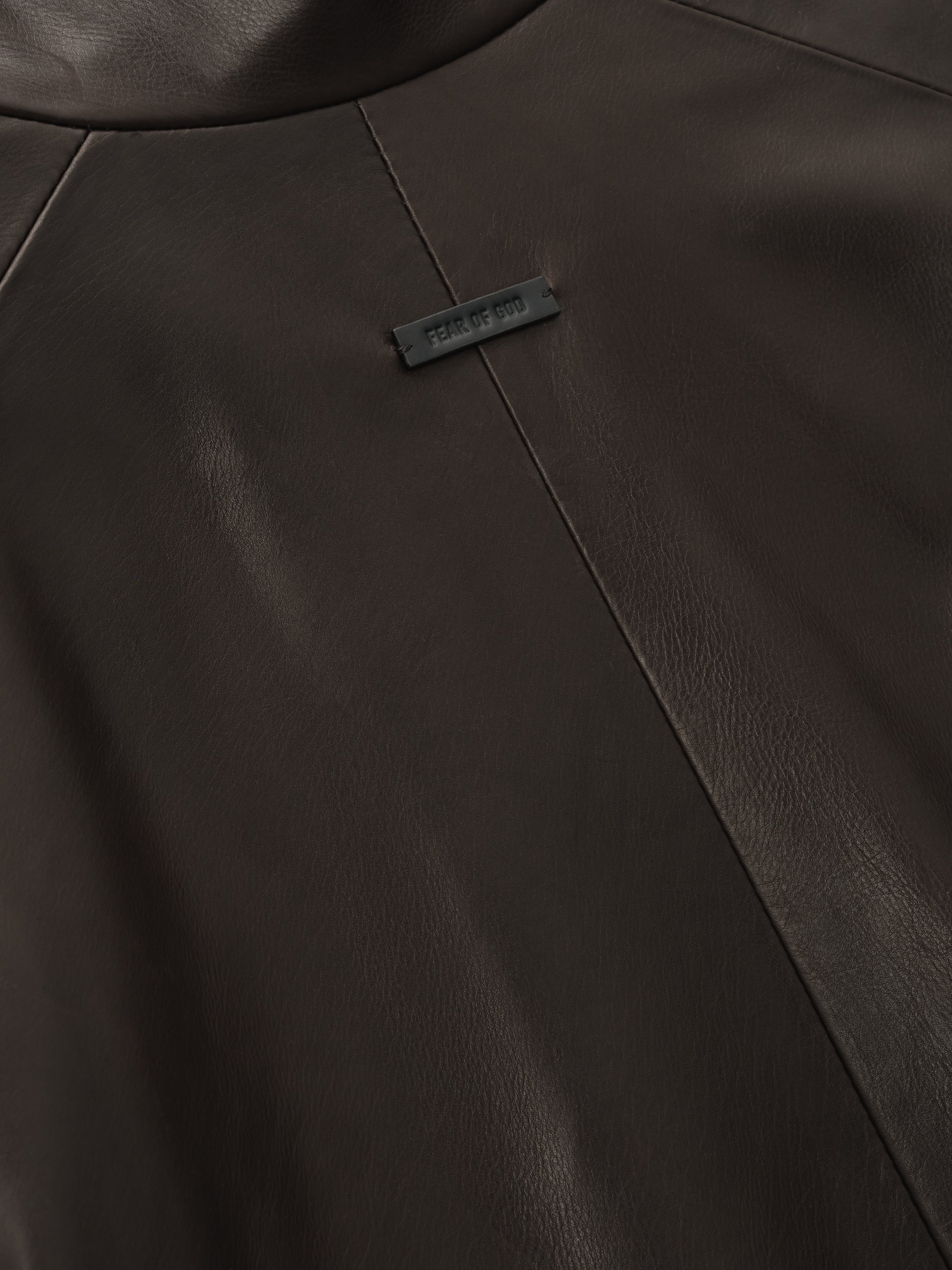 close-up of dark brown full-grain calfskin leather with embossed Fear of God logo tag on women's coat