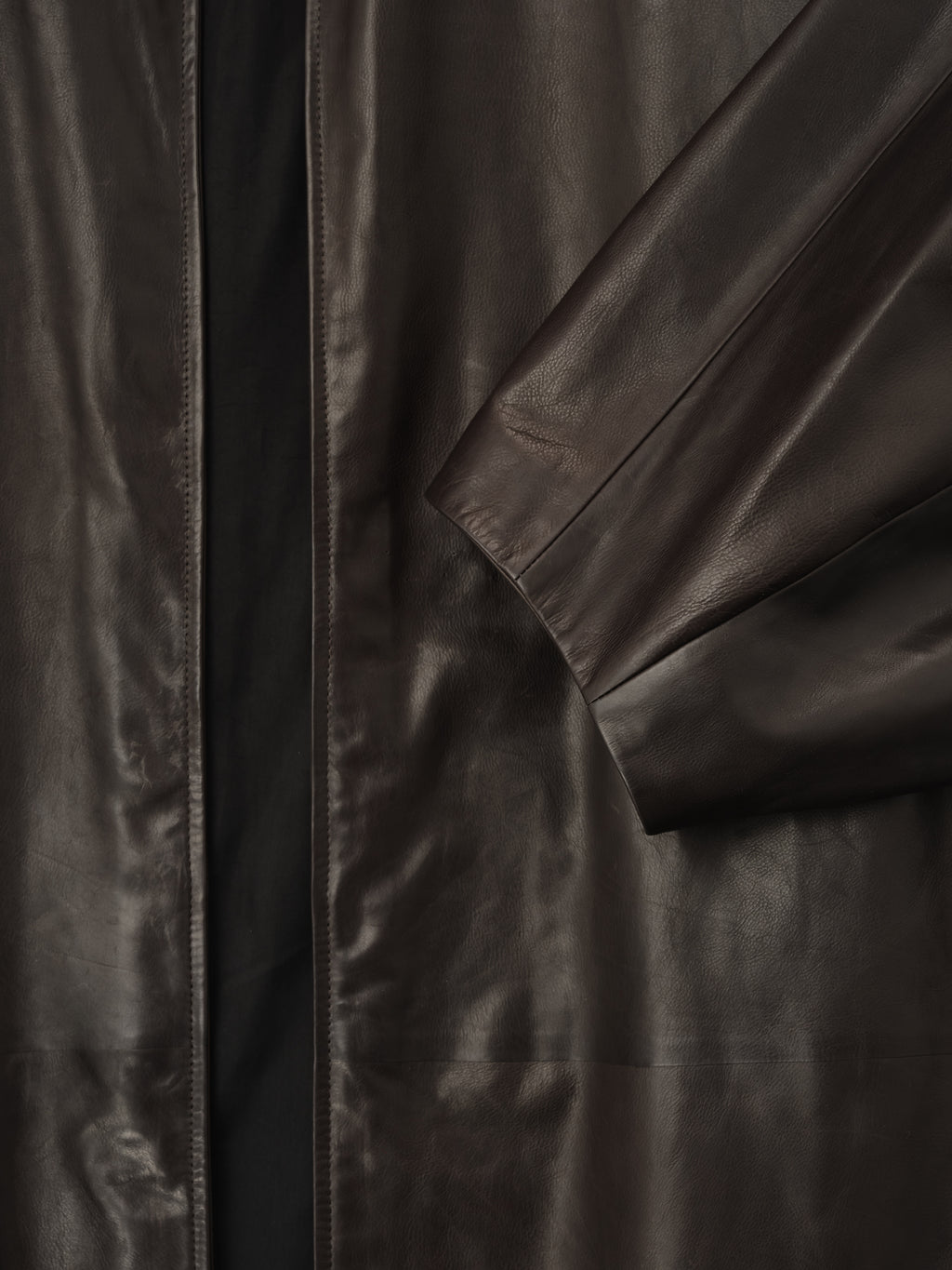 close-up of dark brown full-grain calfskin leather sleeve and front panel with smooth finish on women's coat