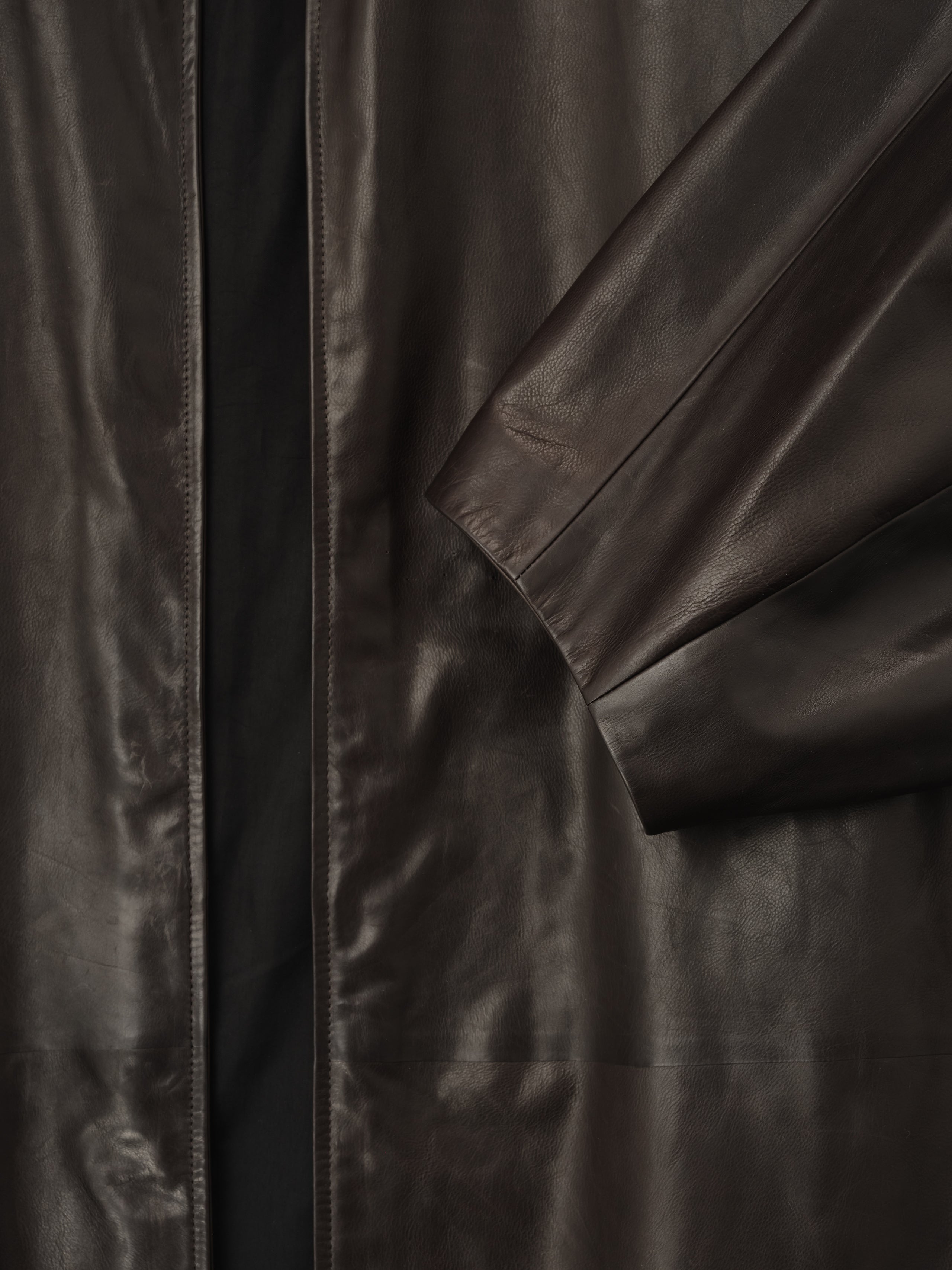 close-up of dark brown full-grain calfskin leather sleeve and front panel with smooth finish on women's coat