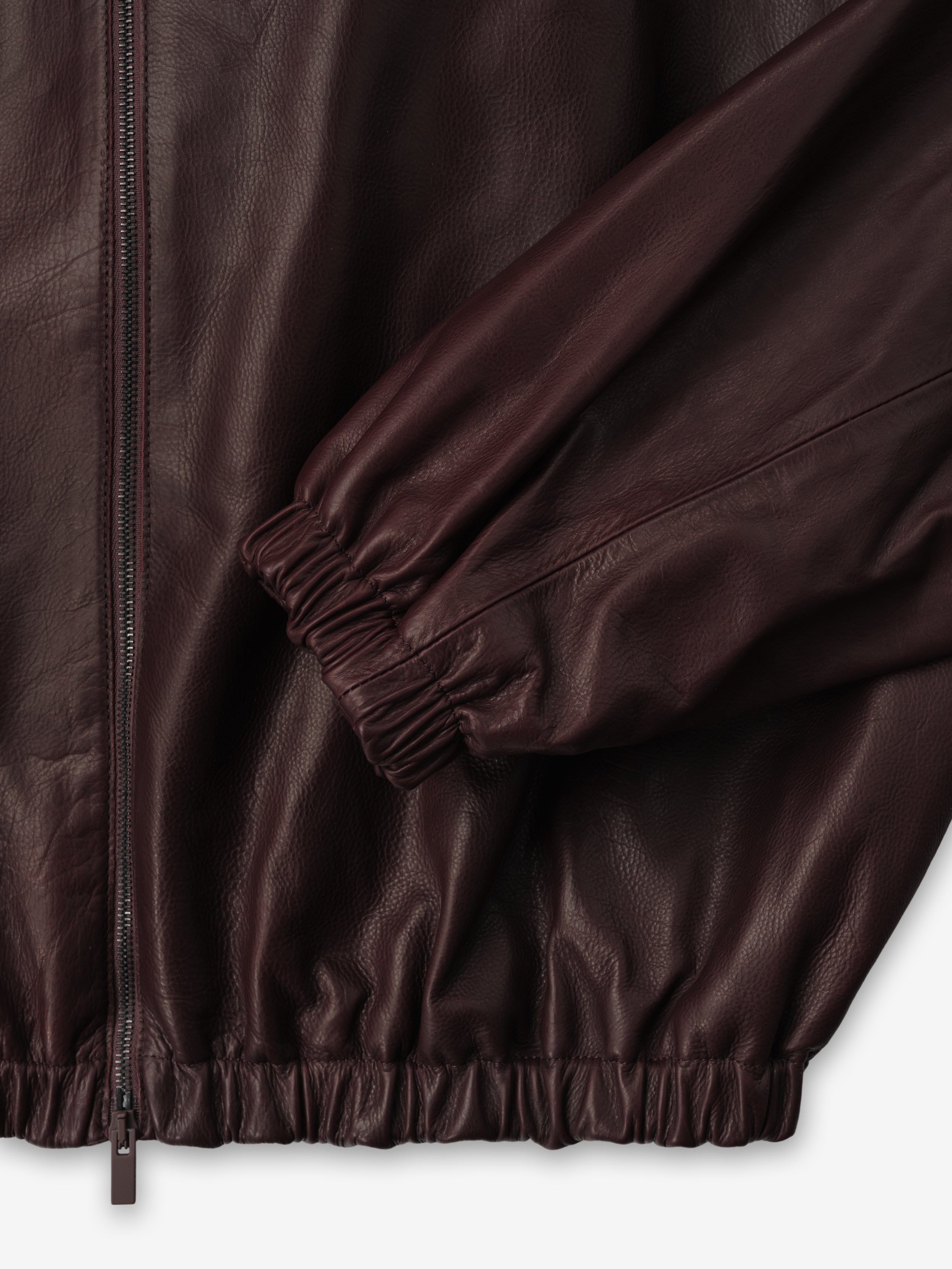 close-up of burgundy full-grain calfskin leather track jacket with elasticated cuffs, hem, and front zipper closure