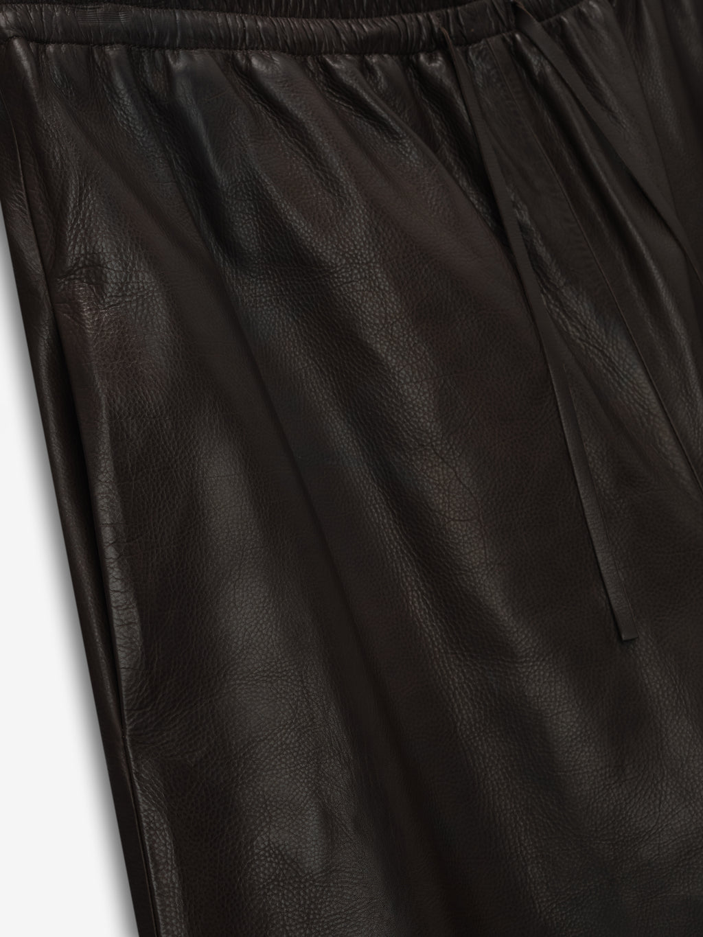 close-up of black full-grain calfskin leather baggy shorts with elastic drawstring waistband and smooth texture
