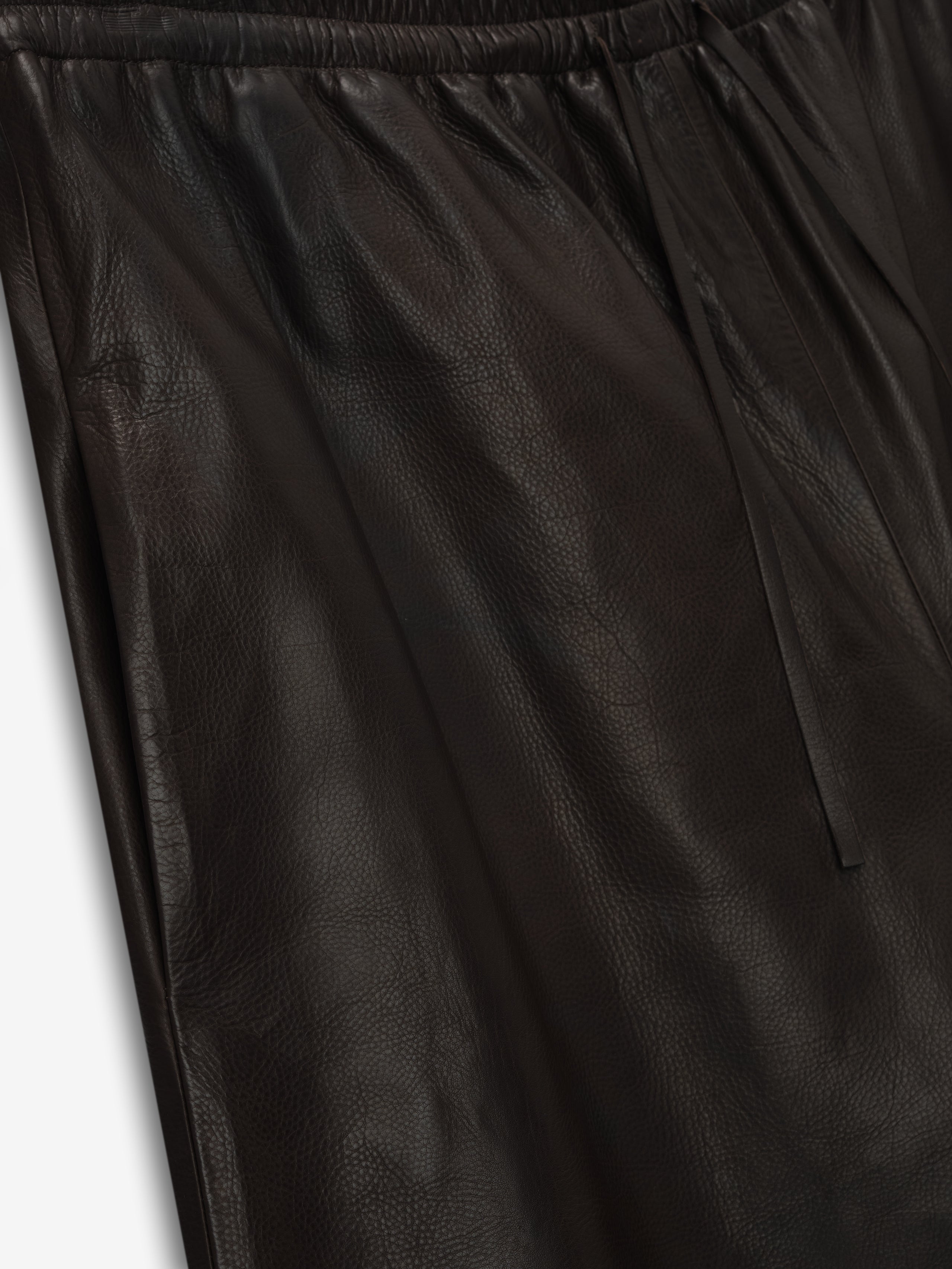close-up of black full-grain calfskin leather baggy shorts with elastic drawstring waistband and smooth texture