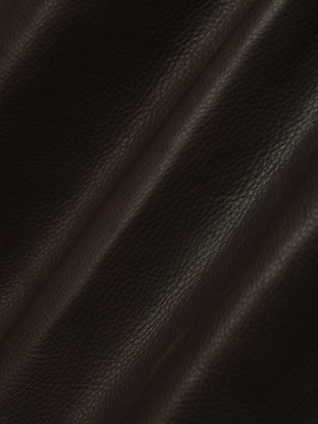 dark brown full-grain calfskin leather with natural grain texture and subtle sheen on women's shorts fabric