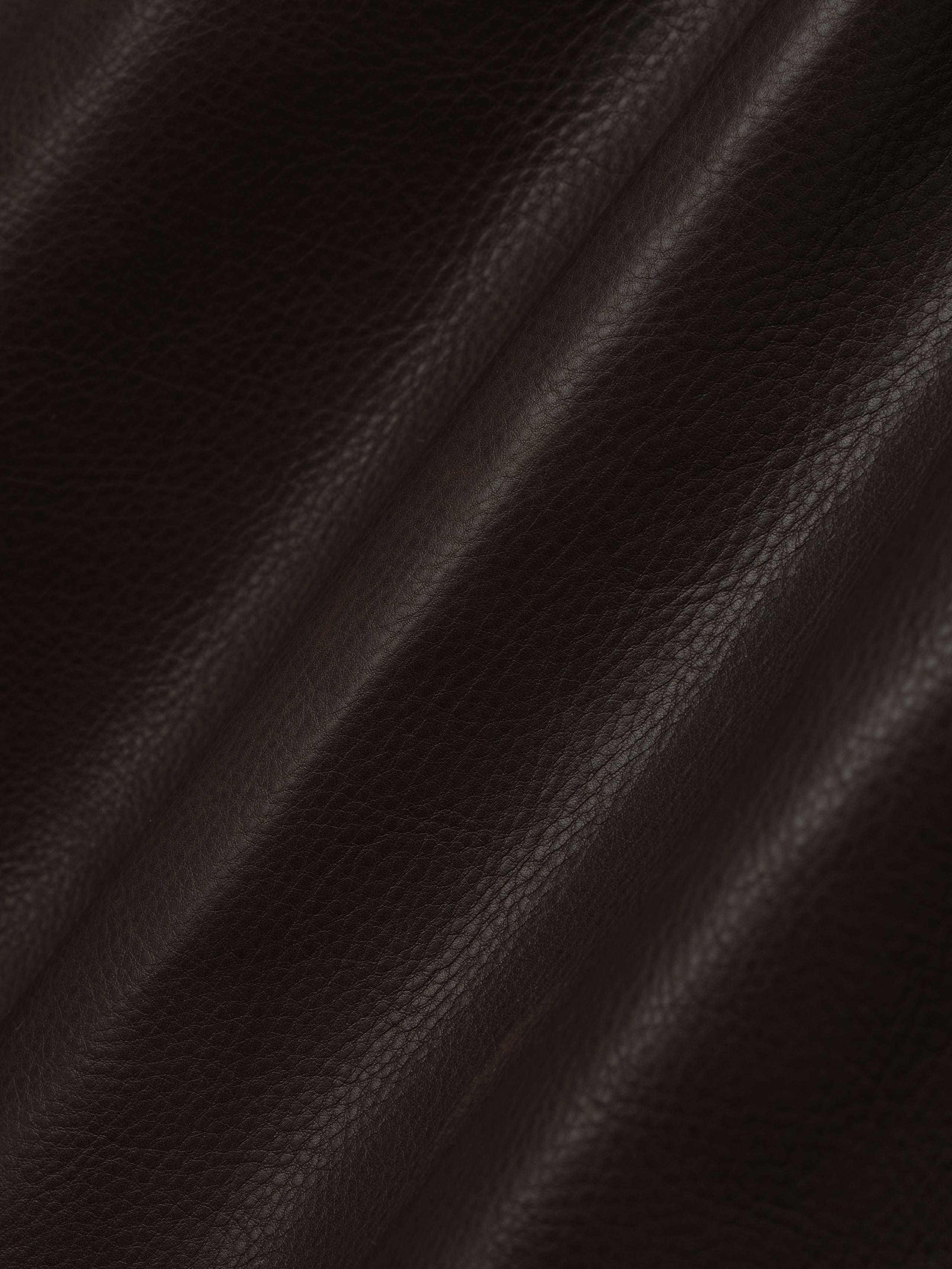 dark brown full-grain calfskin leather with natural grain texture and subtle sheen on women's shorts fabric