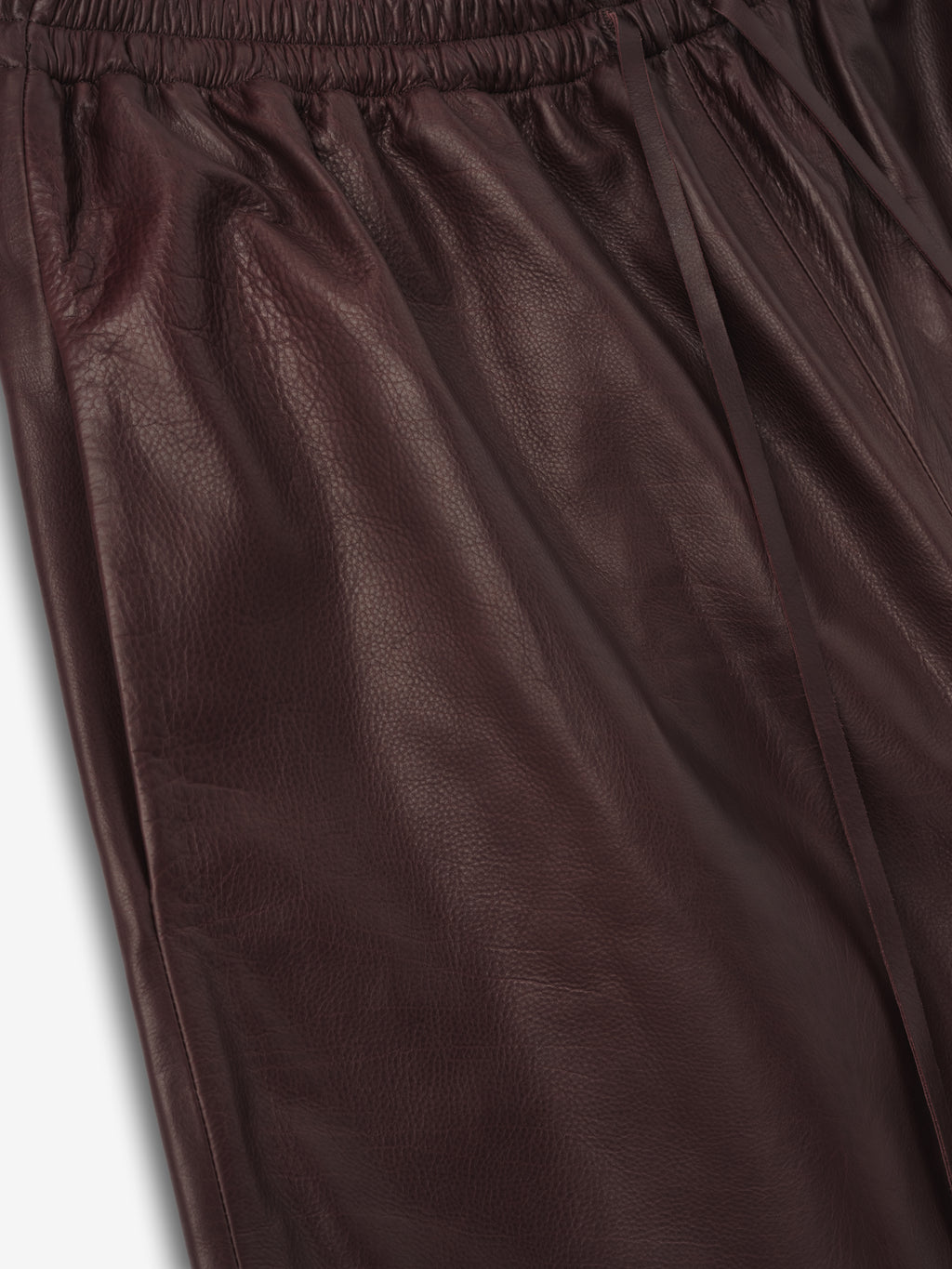 close-up of deep burgundy full-grain calfskin leather with elastic waistband and drawstring on women's shorts