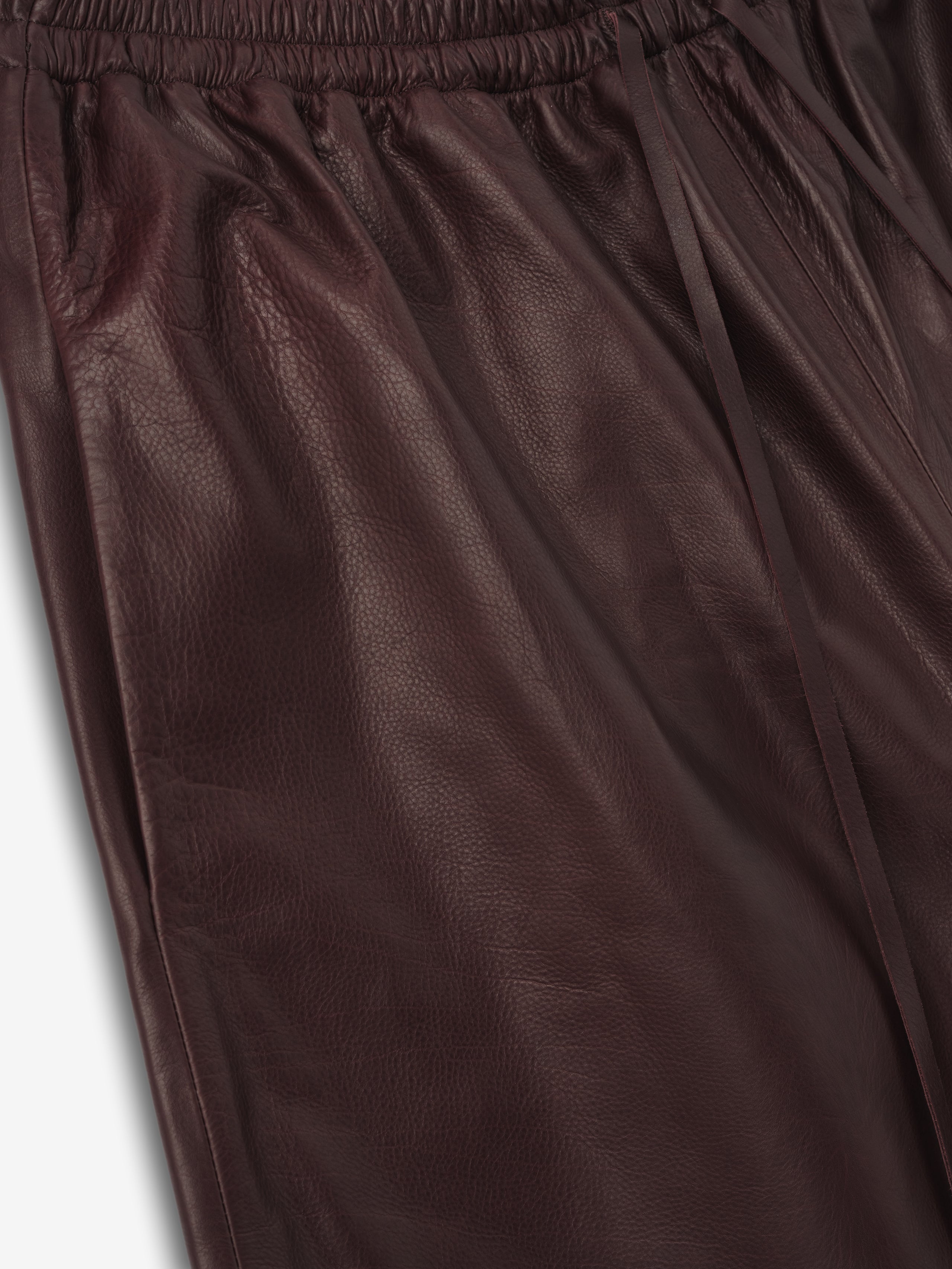 close-up of deep burgundy full-grain calfskin leather with elastic waistband and drawstring on women's shorts