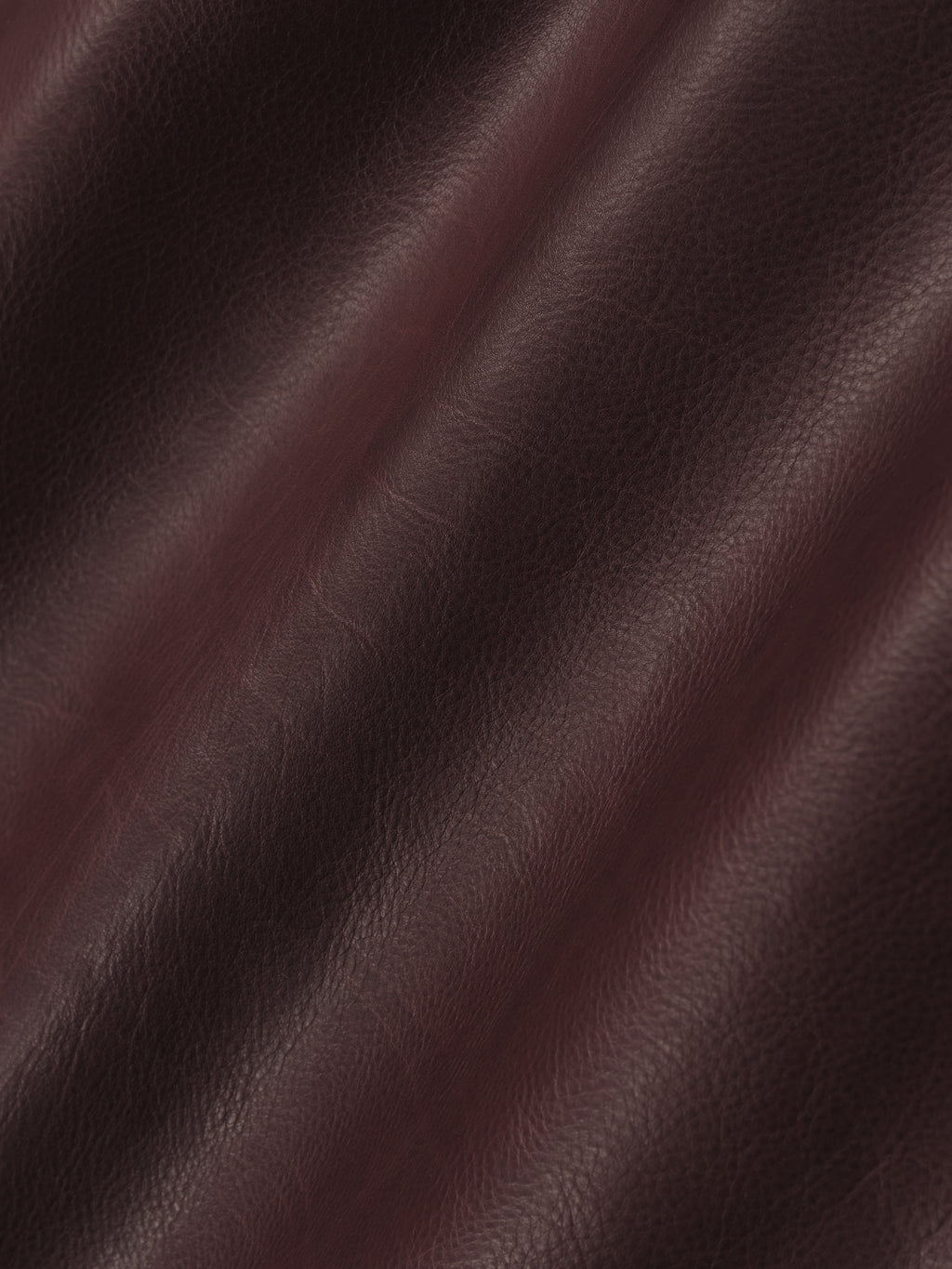 close-up of deep burgundy full-grain calfskin leather with natural grain and soft sheen texture