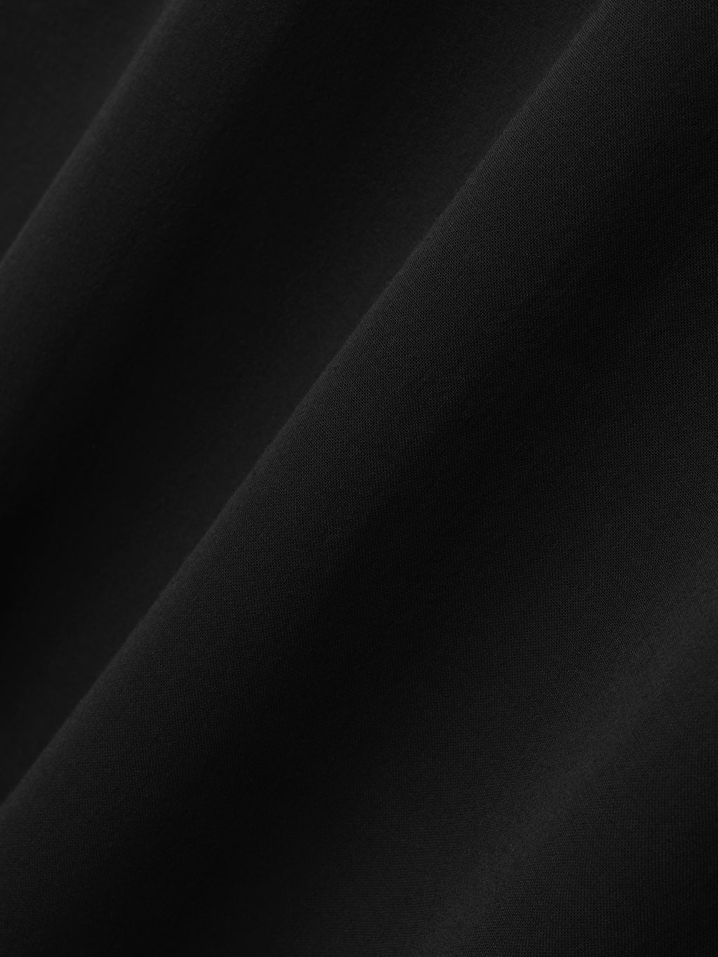 close-up of smooth black wool viscose fabric with subtle sheer texture and soft drape on women's sleeveless tee