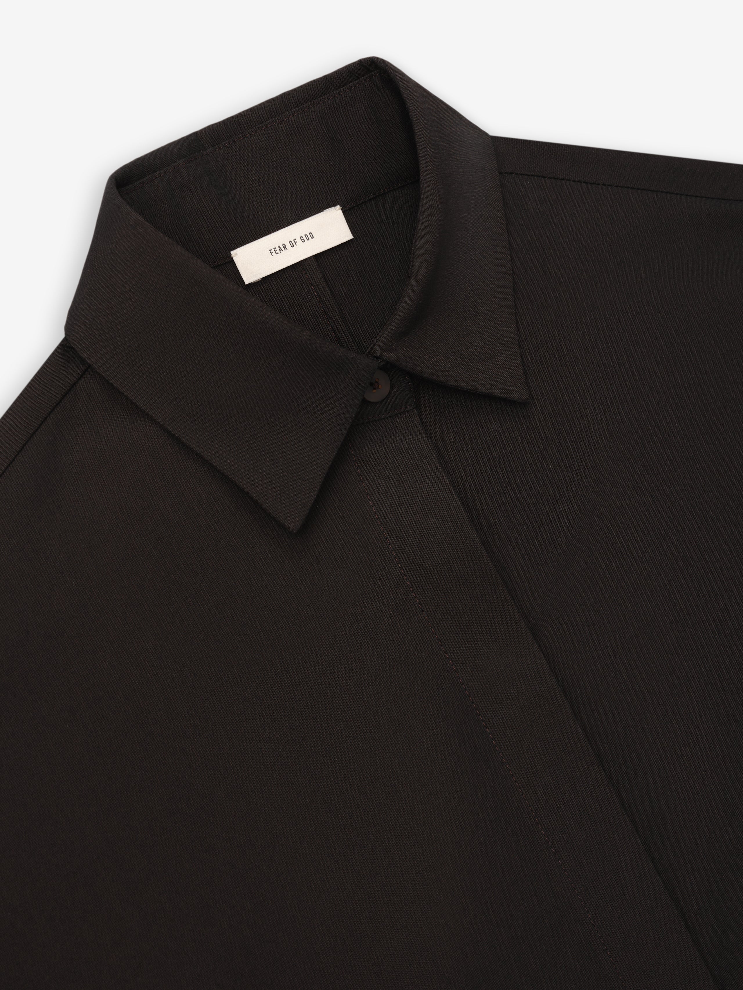 Close-up of black collared shirt with concealed button placket and smooth fabric texture on a white background