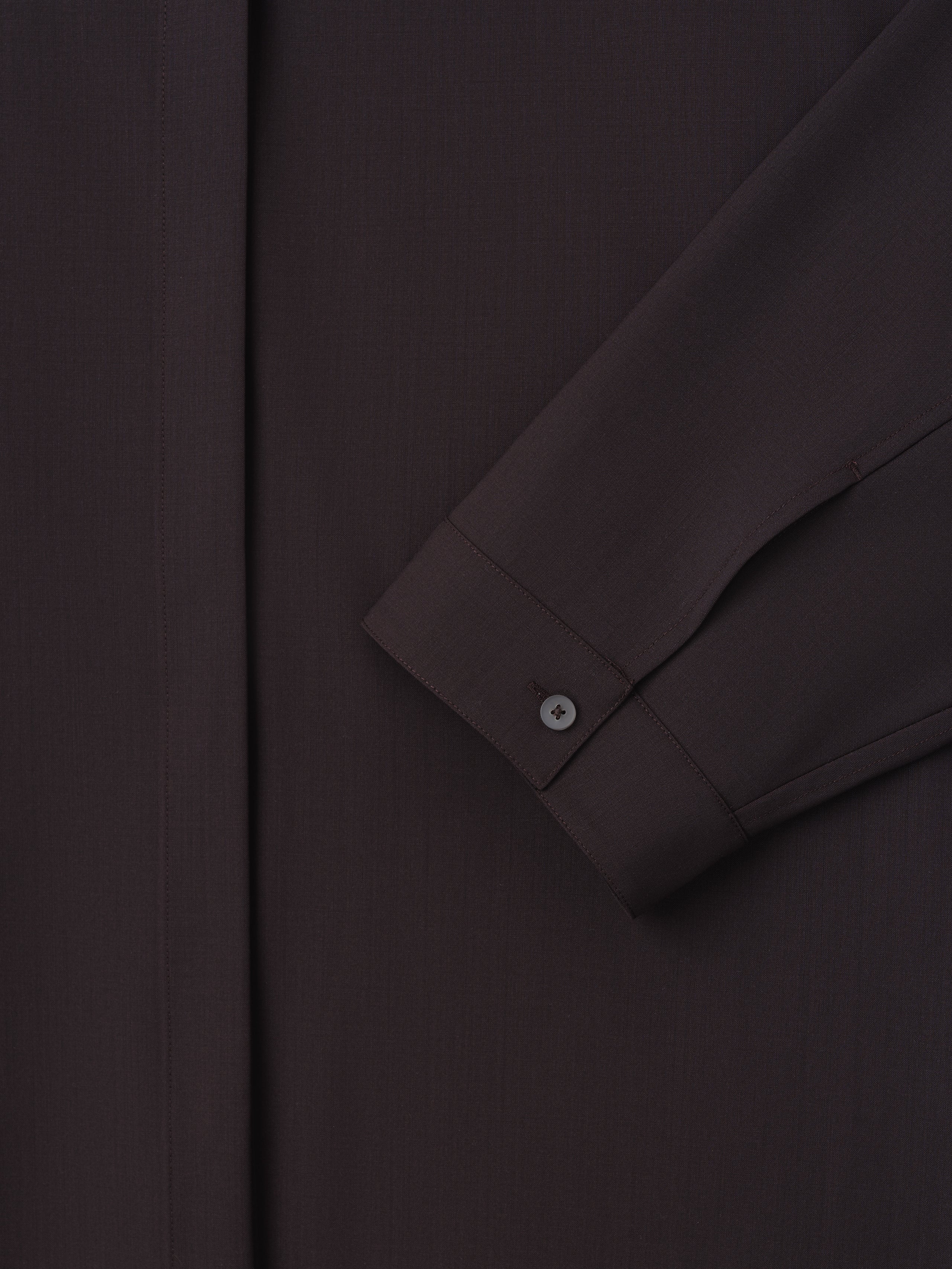 close-up of dark relaxed fit women's shirt sleeve with small buttoned cuff and hidden front placket in lightweight wool canvas