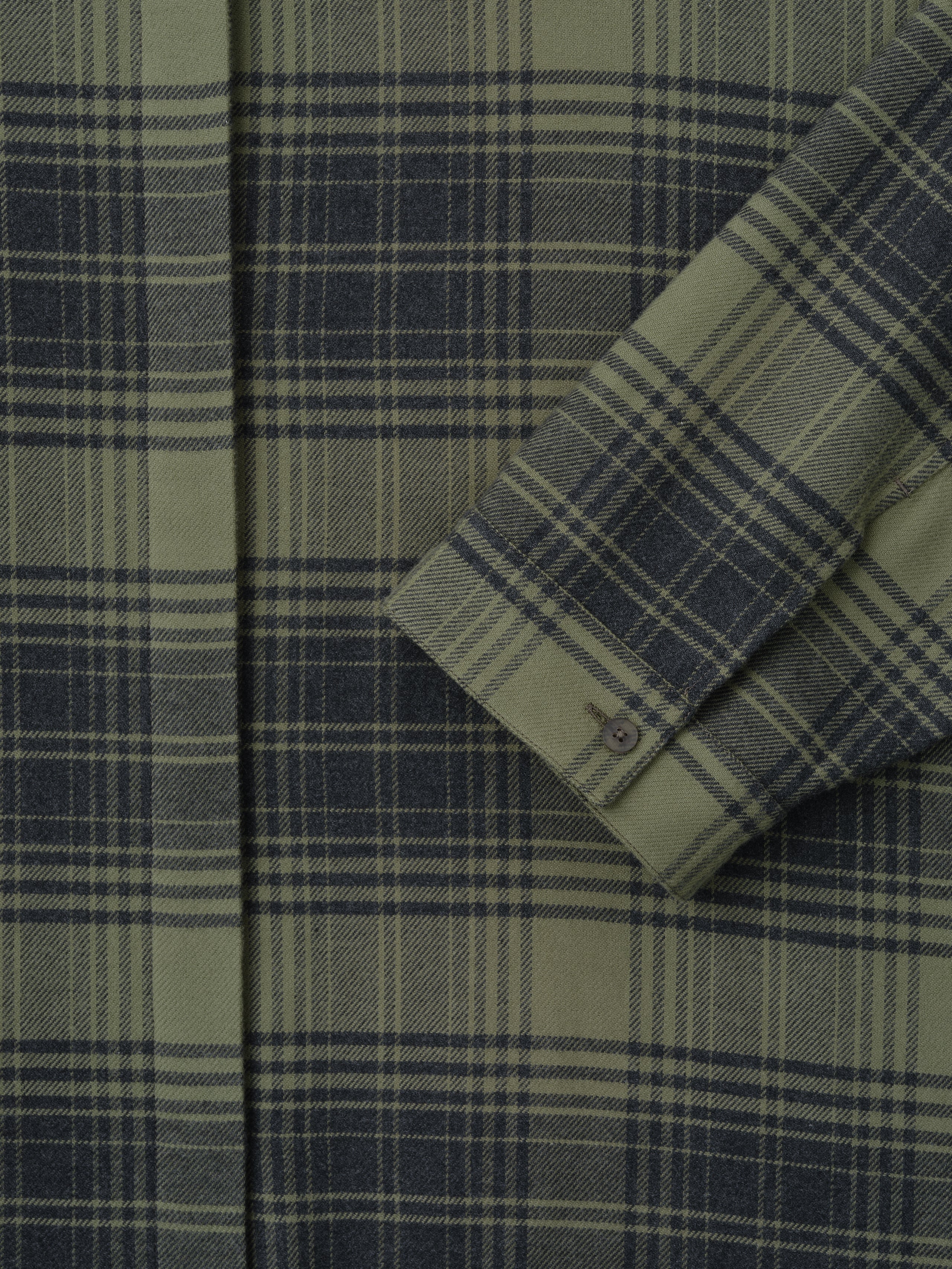 close-up of green plaid cotton flannel women's shirt sleeve with small buttoned cuff and concealed front placket