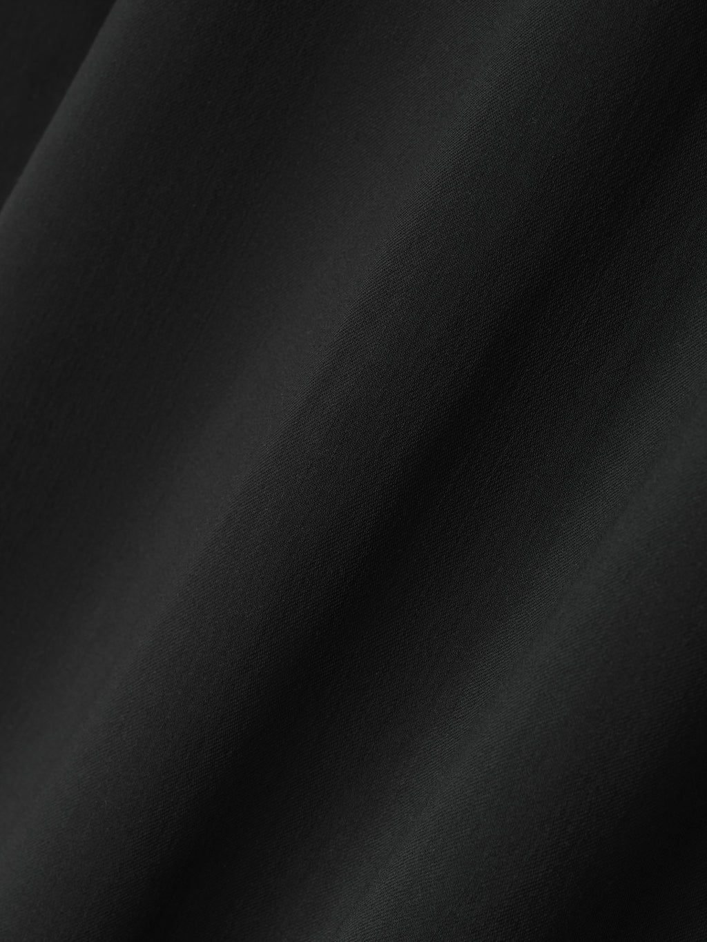close-up of smooth black superfine wool twill fabric with subtle texture and soft drapey appearance