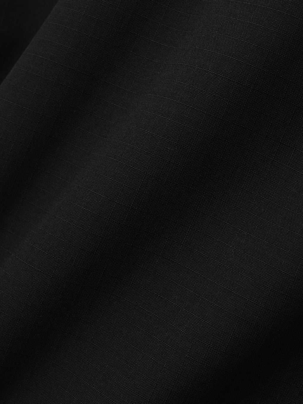 detailed view of black compact wool ripstop fabric with subtle textured grid pattern and soft drape