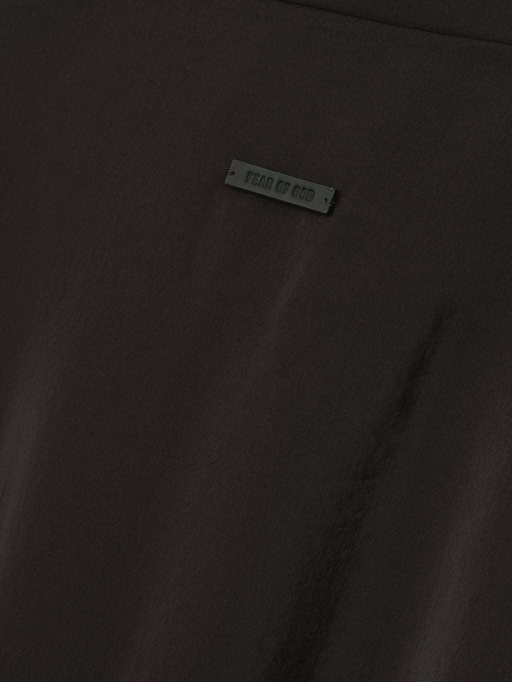close-up of black technical crinkle viscose fabric with small Fear of God branded rubber tag detail