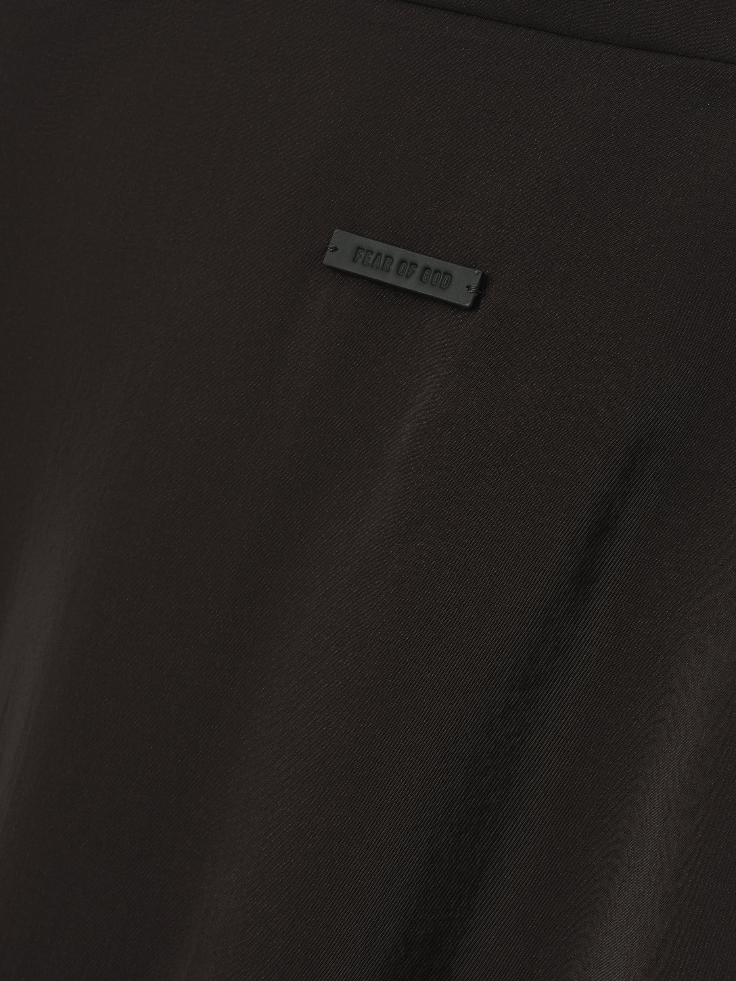close-up of black technical crinkle viscose fabric with small Fear of God branded rubber tag detail