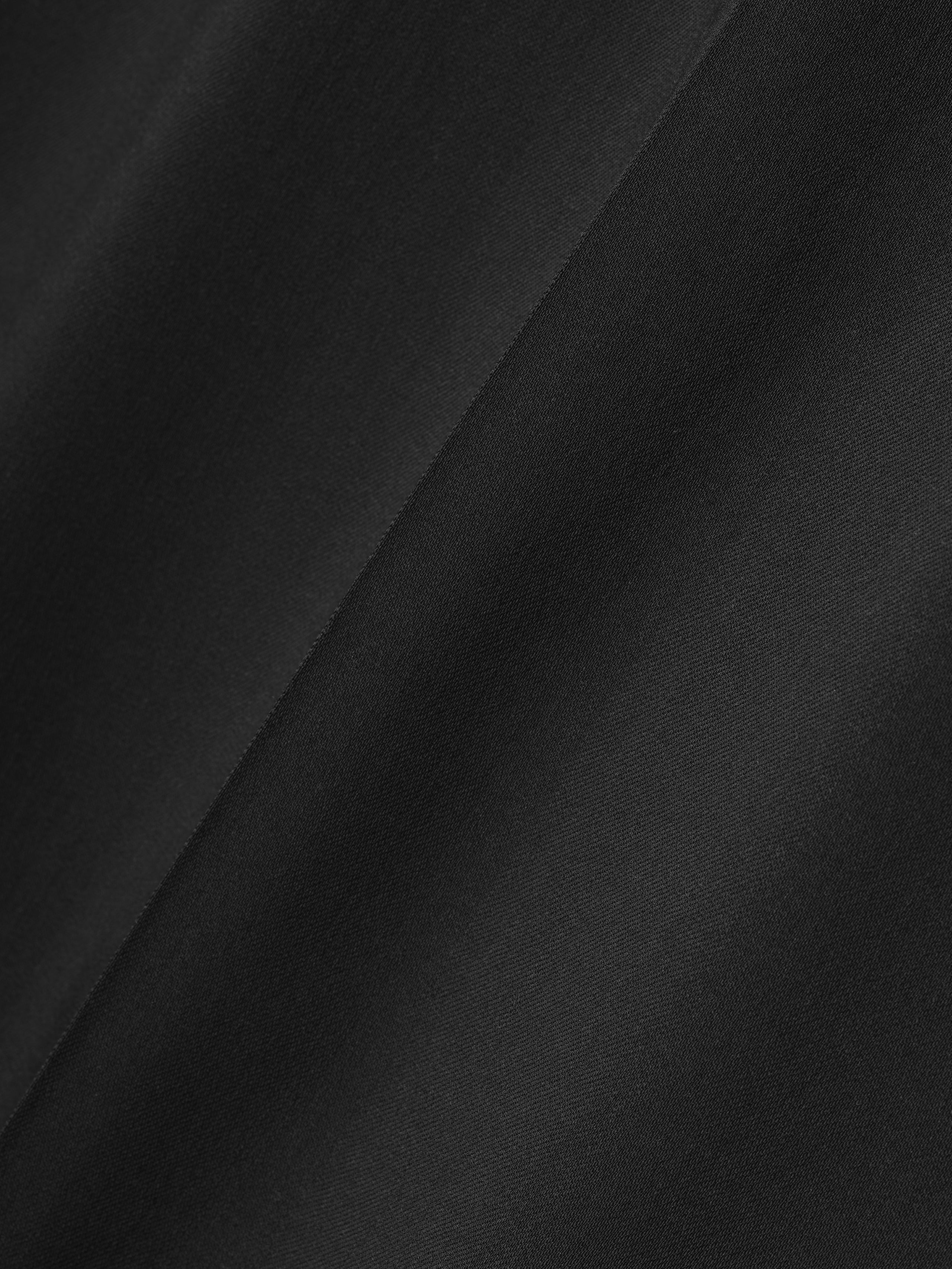 close-up of smooth black fabric with subtle diagonal texture detail on wide leg pants