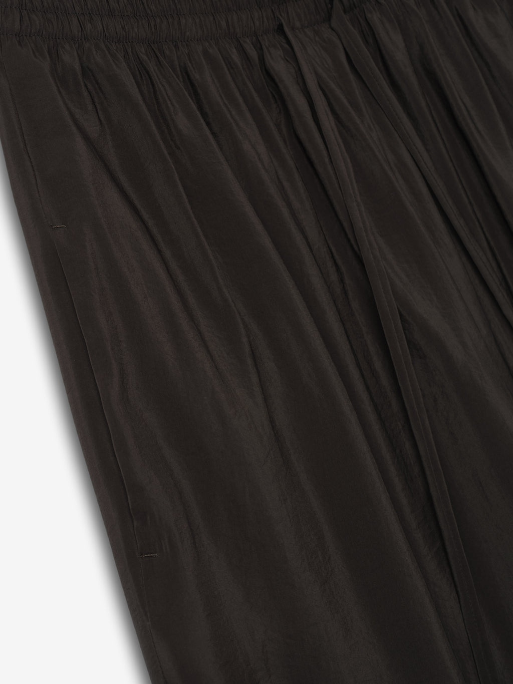 close-up of black crinkle viscose pants with elastic waistband and wide-leg drape in lightweight semi-sheer fabric