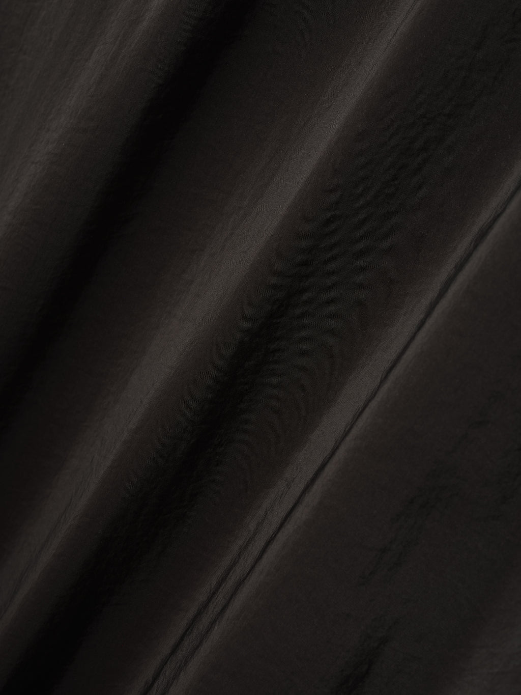 close-up of lightweight technical crinkle viscose fabric with subtle sheen and textured surface in dark color