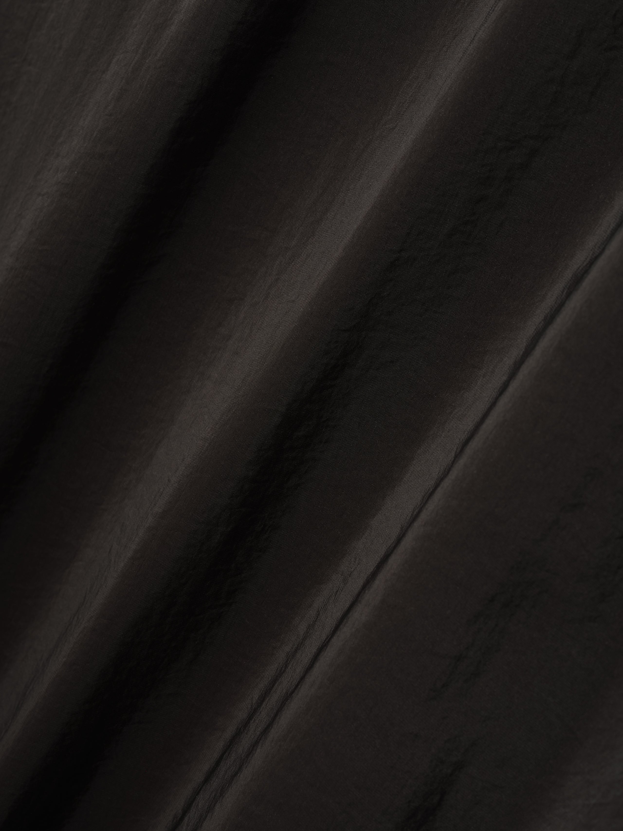 close-up of lightweight technical crinkle viscose fabric with subtle sheen and textured surface in dark color