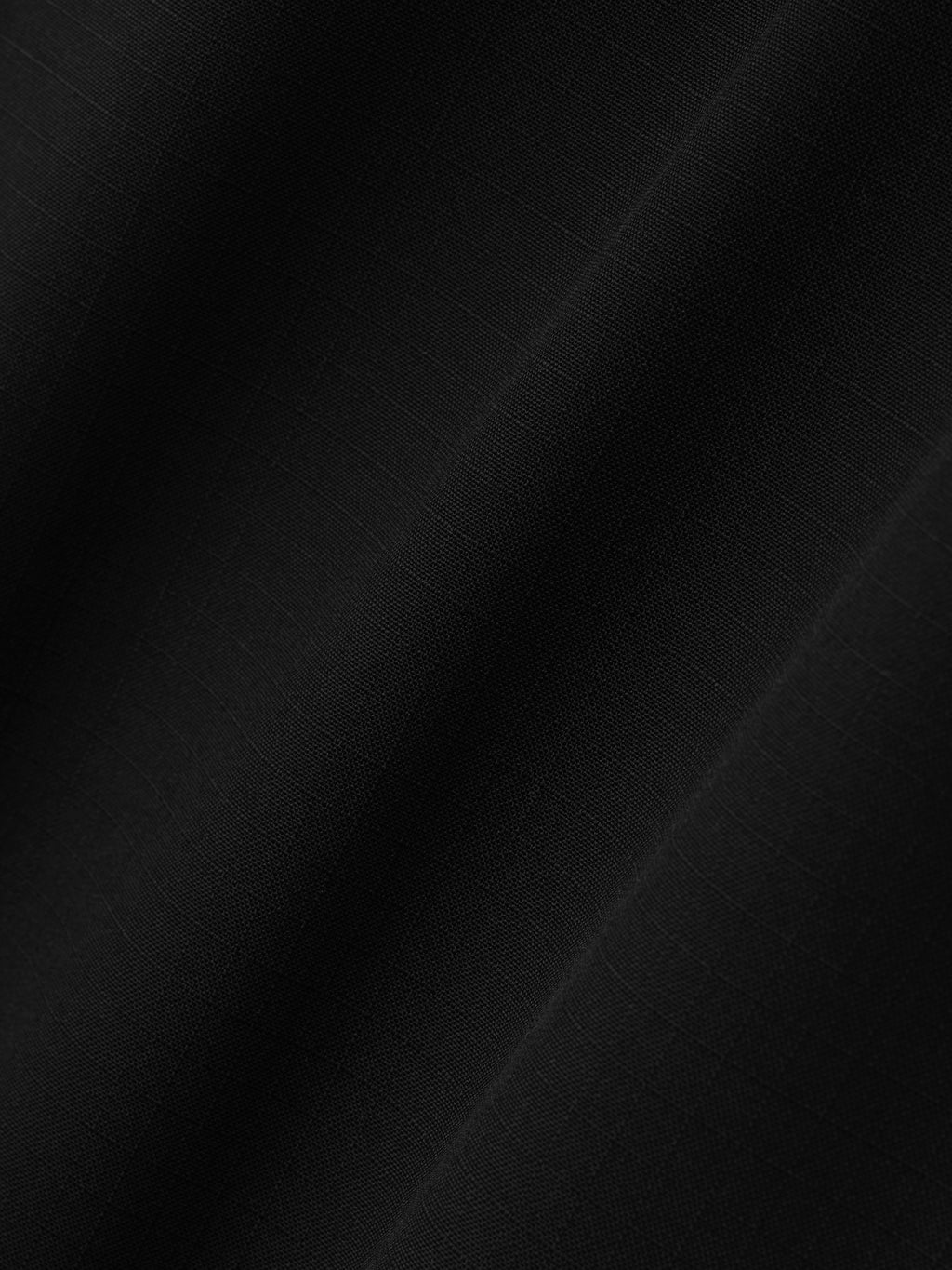 close-up of black compact rip-stop virgin wool fabric with subtle grid texture and smooth matte finish