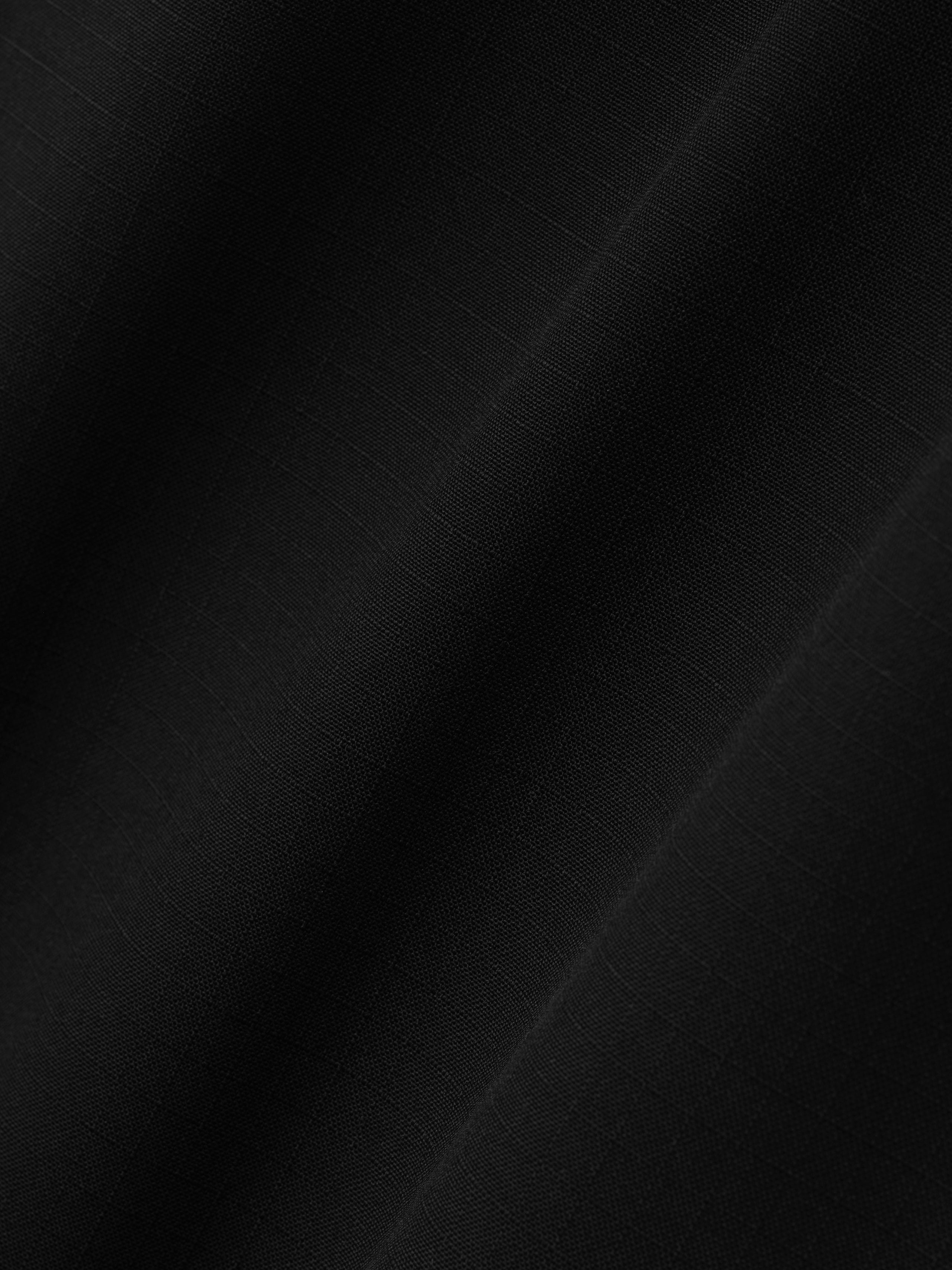 close-up of black compact rip-stop virgin wool fabric with subtle grid texture and smooth matte finish