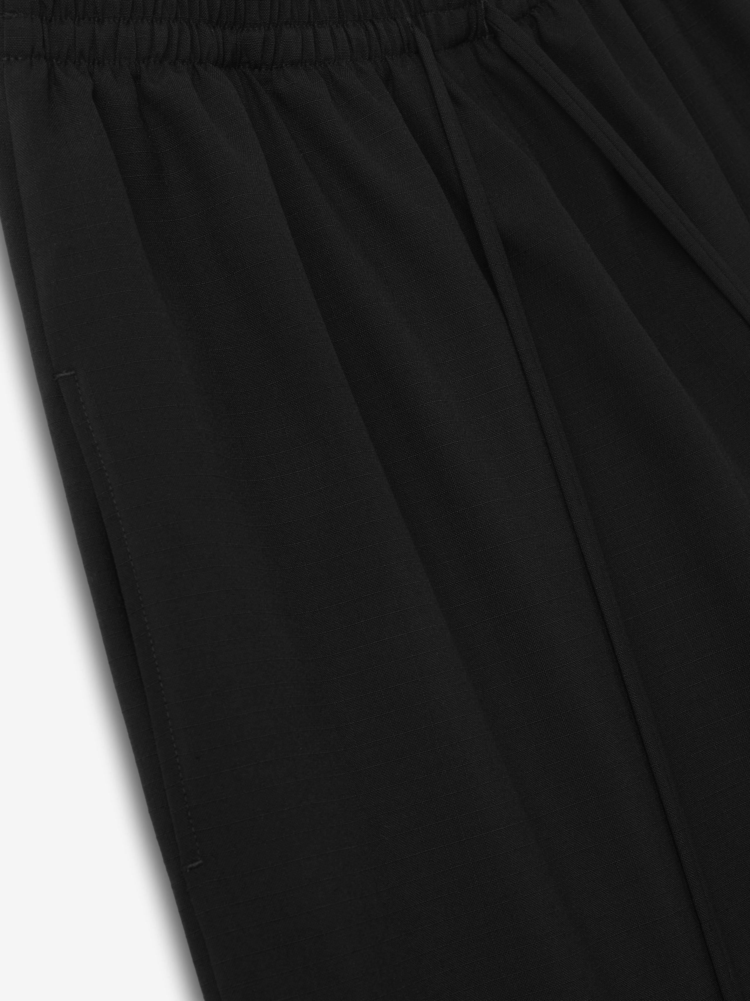 close-up of black womens wide-leg drawstring shorts in lightweight compact rip-stop virgin wool fabric