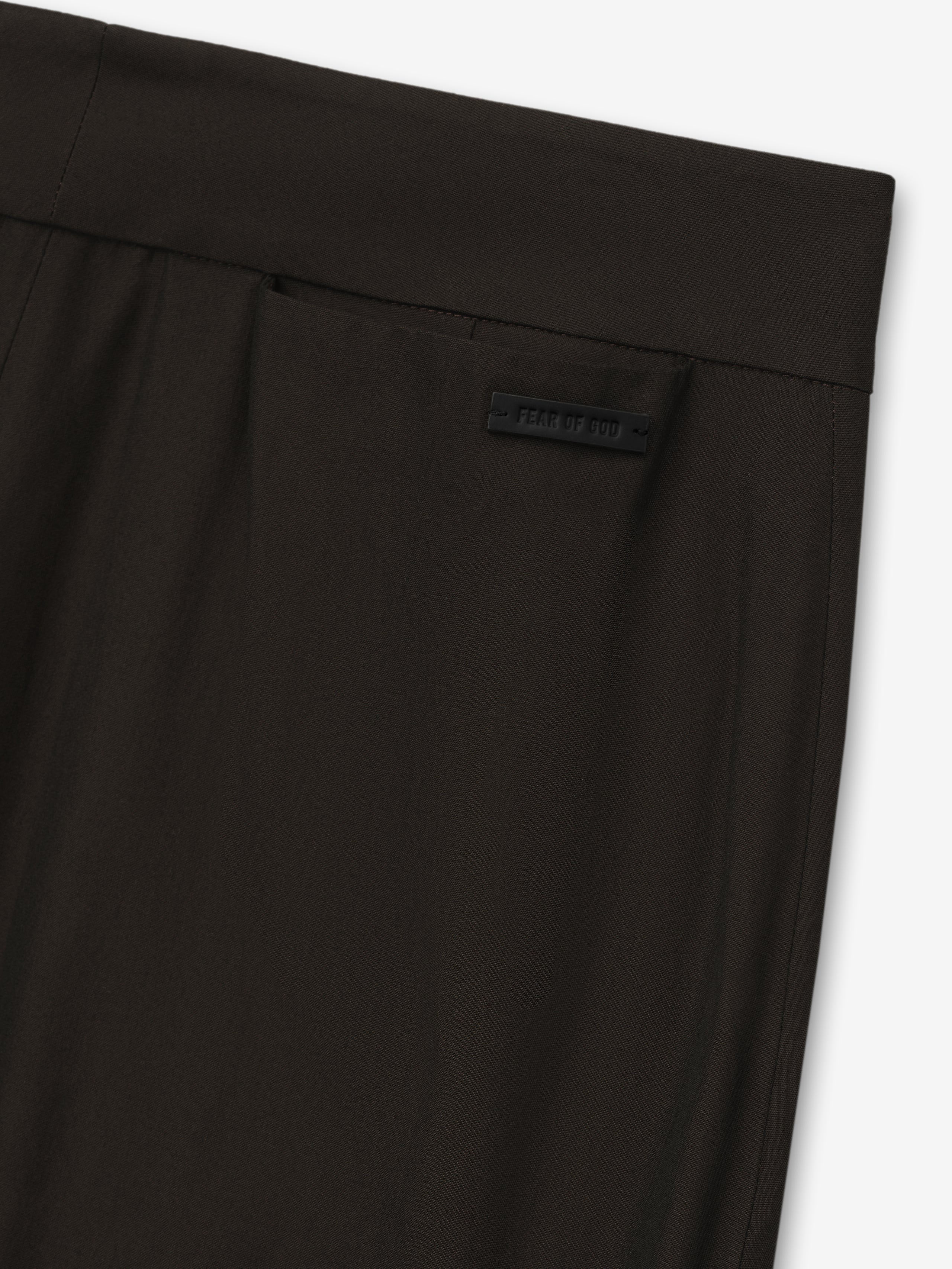 close-up of dark brown womens worker pants waistband with subtle branded label and smooth fabric texture