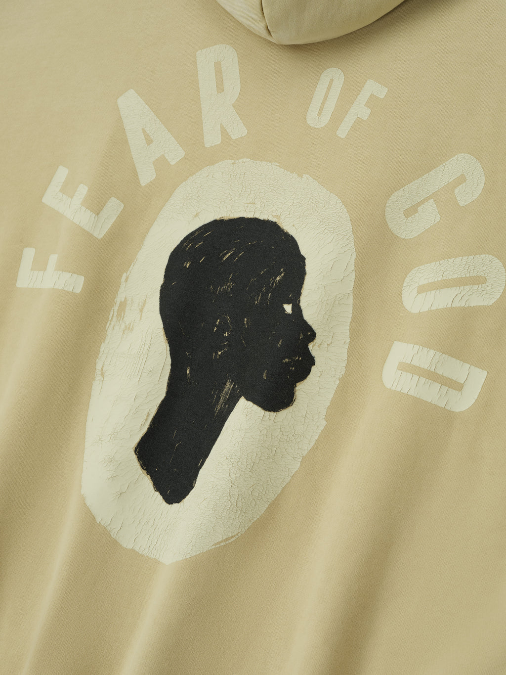 Close-up of clay Liberation Now Hoodie showing textured black profile silhouette with faded white "FEAR OF GOD" text FGDSYF-FLC004U gallery 0