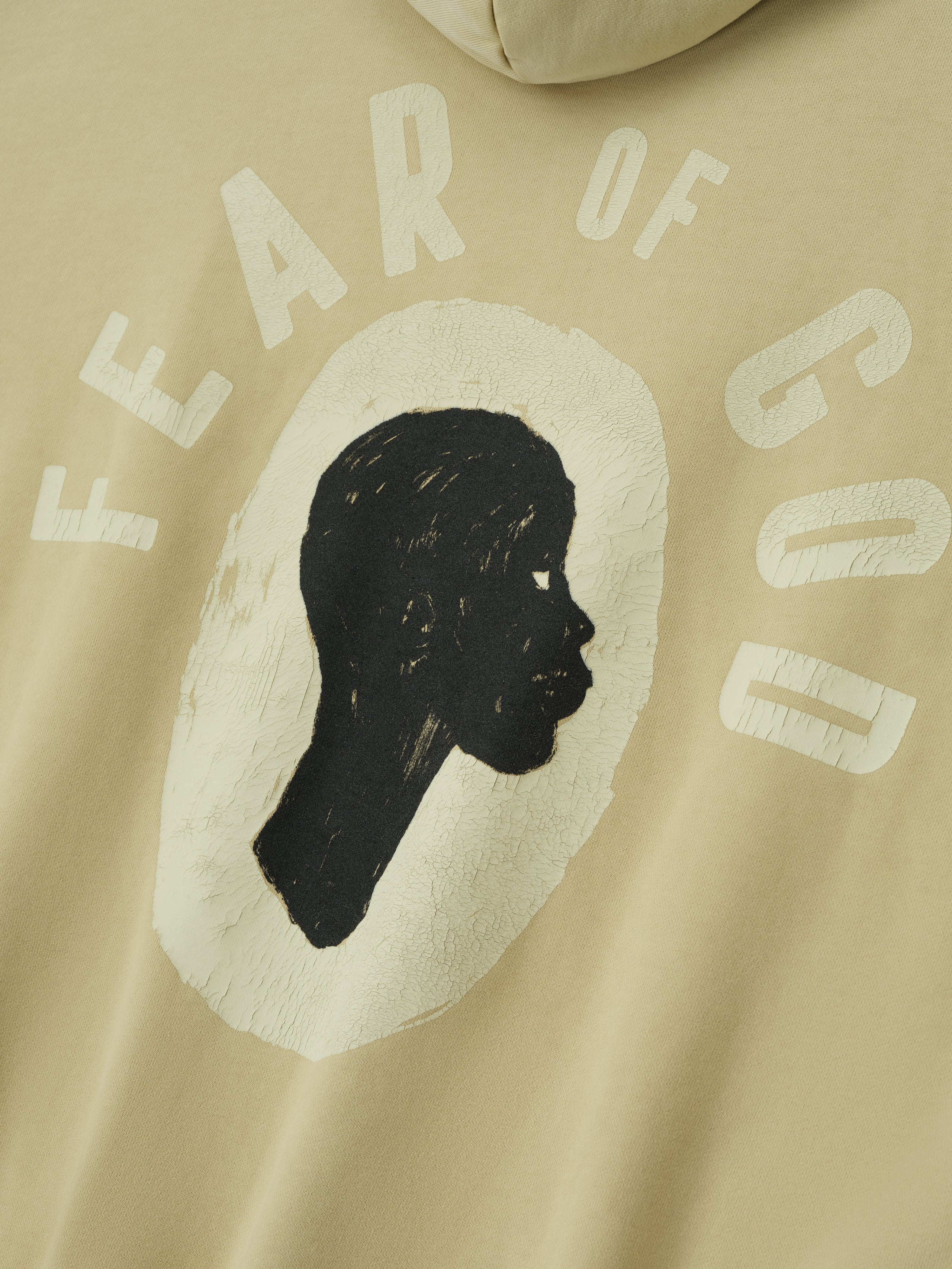 Close-up of clay Liberation Now Hoodie showing textured black profile silhouette with faded white "FEAR OF GOD" text FGDSYF-FLC004U gallery 0