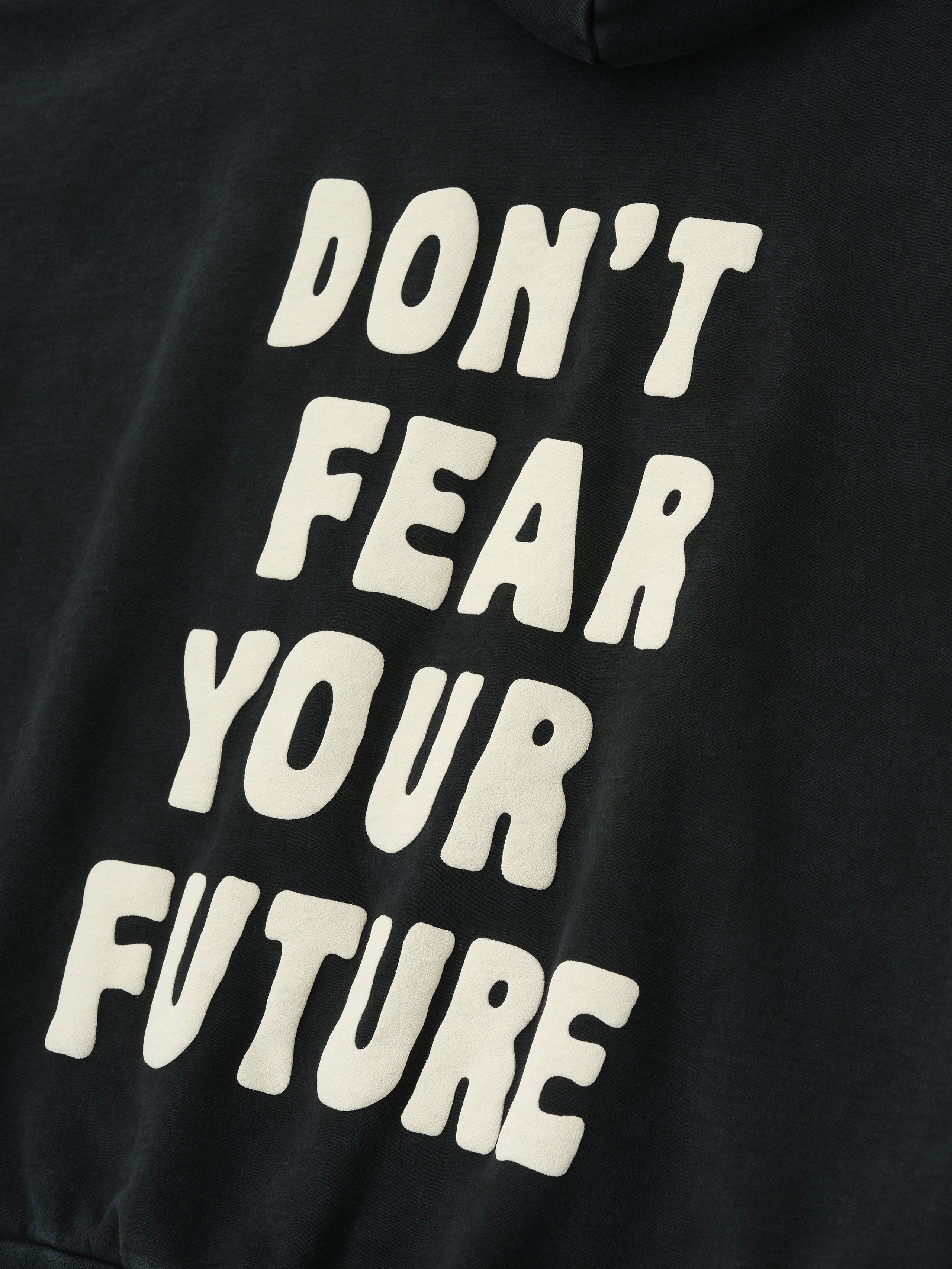 Close-up of black DSYF Hoodie showing bold white "DON'T FEAR YOUR FUTURE" text on back, gallery image zero.