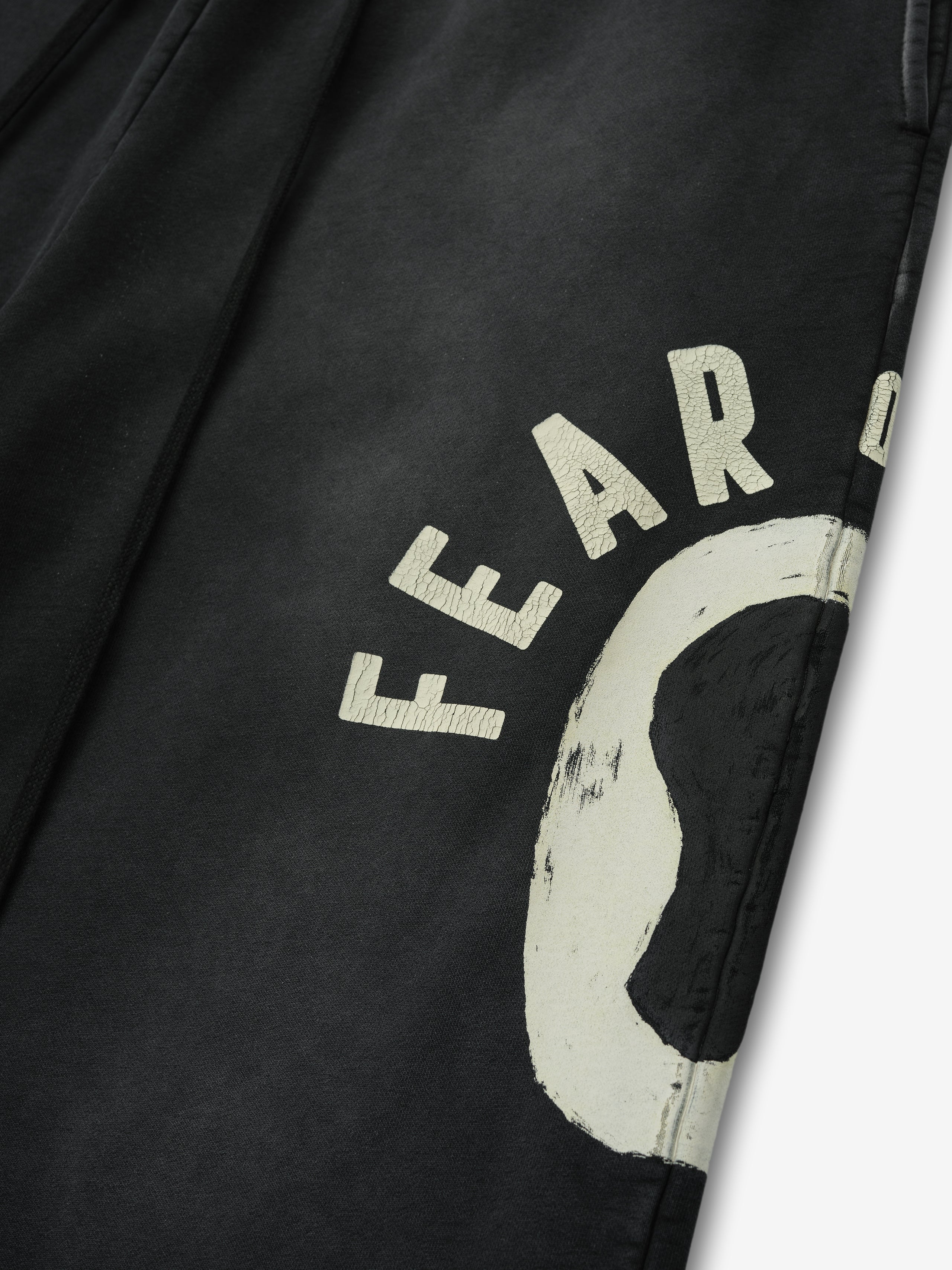 Detailed close-up of black DSYF Wide Leg Sweatpant showing off-white distressed "FEAR" text and graphic near thigh area in first gallery image