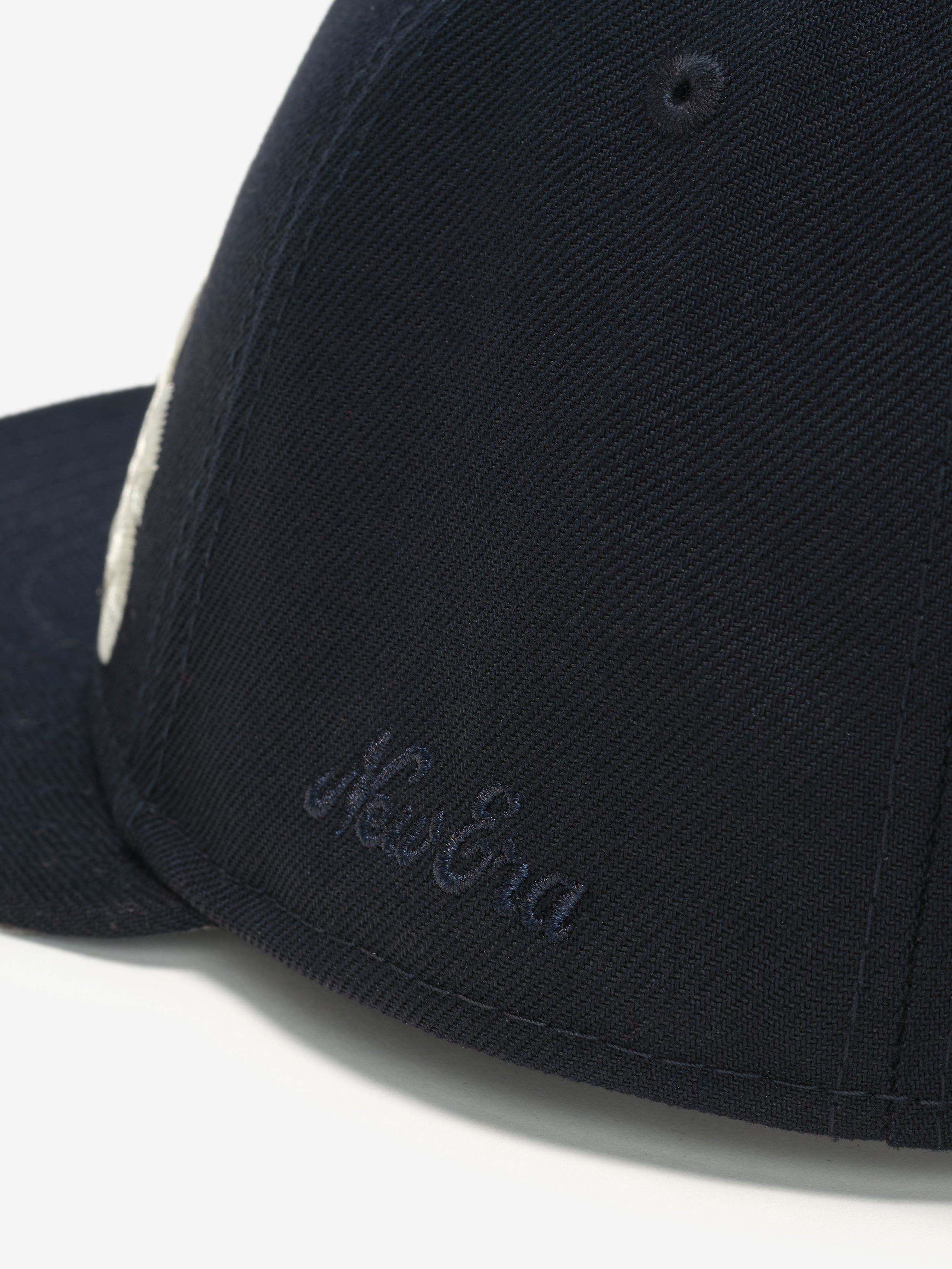 Close-up side view of navy Cowboys 9Fifty RC Snapback showing subtle embroidered New Era logo on fabric panel, gallery image 0