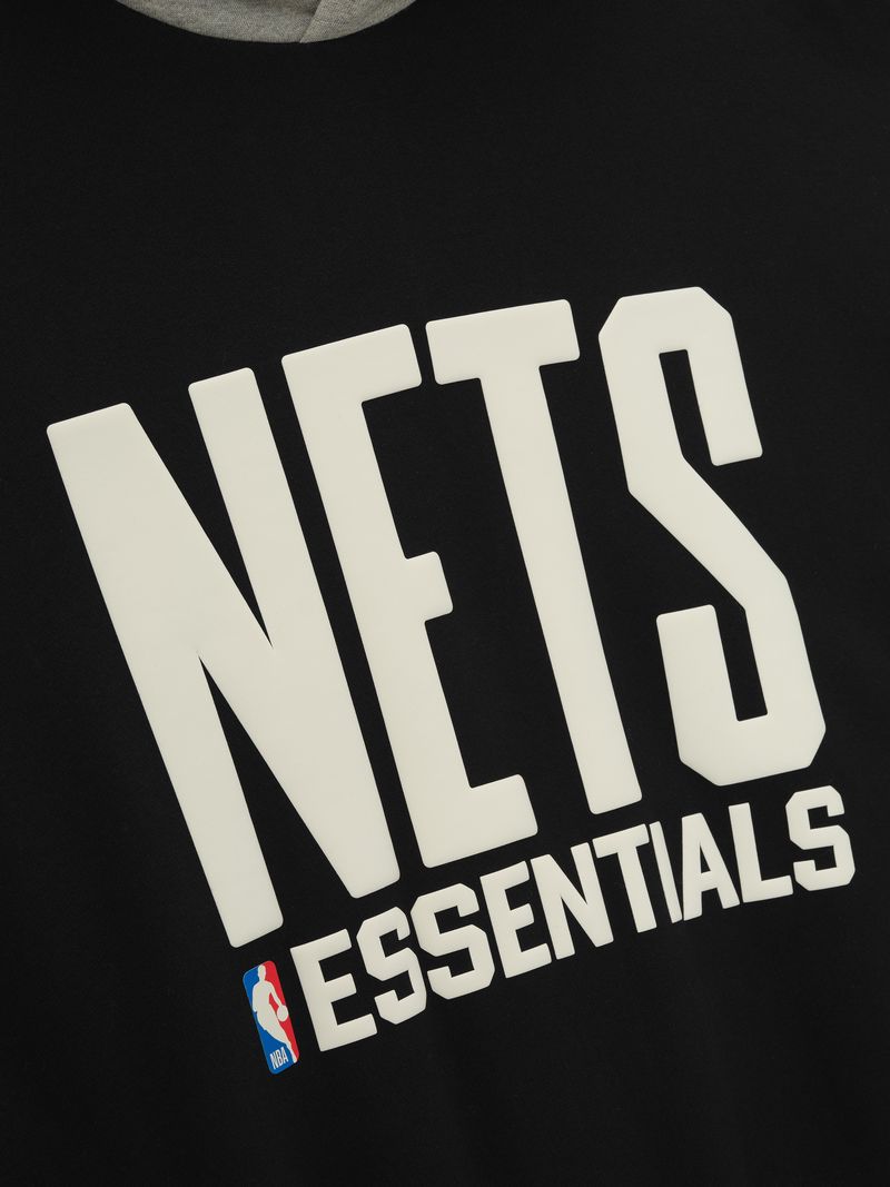 Close-up of black hoodie with large white NETS lettering, ESSENTIALS text, and NBA logo on front chest area
