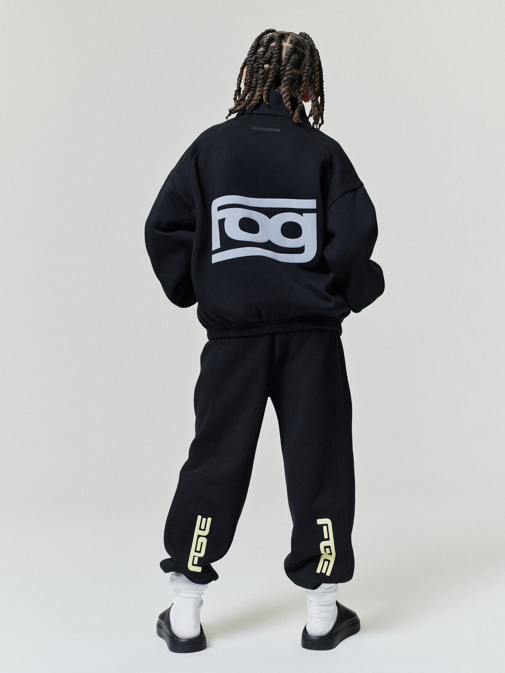 Kids Classic Track Jacket in black shown from the back on a child model with a large back logo and relaxed fit paired with matching pants and sneakers as Outerwear