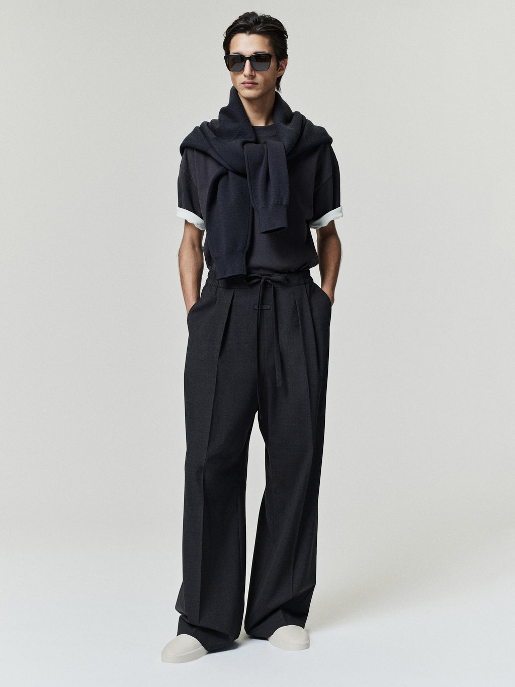 Melange Wool Box Pleat Drawstring Pants in dark charcoal with wide legs and front pleats shown on a model with hands in pockets