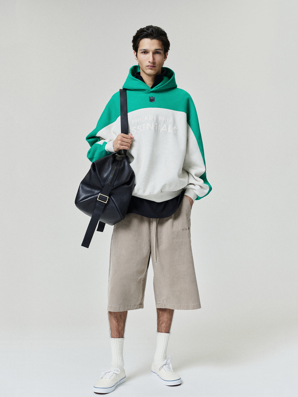 Eagles 90s Relaxed Hoodie green and cream color block pullover modeled with neutral shorts white socks and sneakers shown as a Tops fashion product view