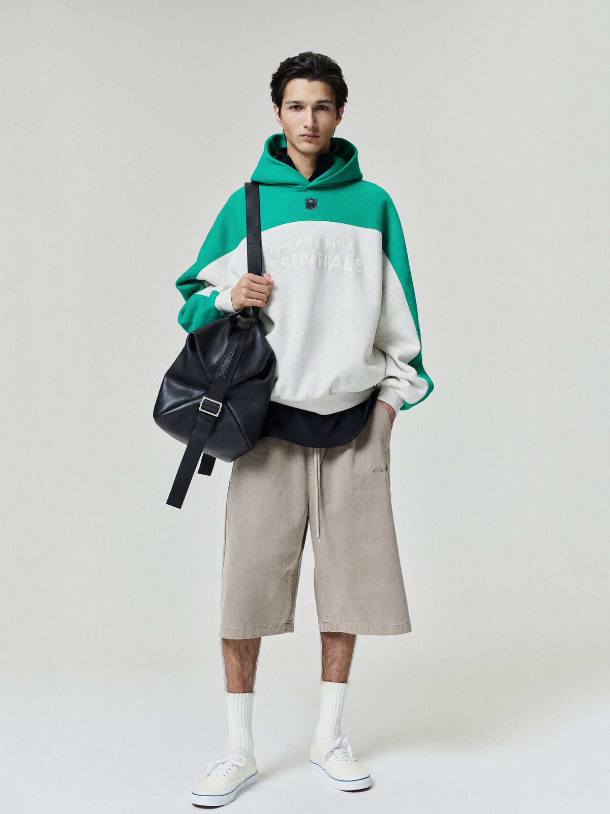 Eagles 90s Relaxed Hoodie green and cream color block pullover modeled with neutral shorts white socks and sneakers shown as a Tops fashion product view