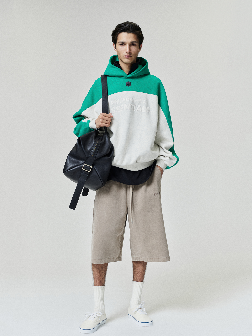 Eagles 90s Relaxed Hoodie in green and white styled with beige shorts a black shoulder bag and white sneakers as Tops