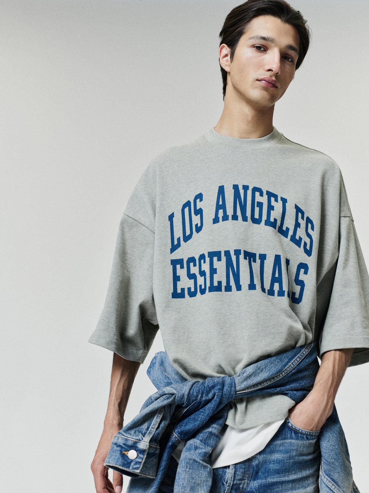 Rams Merch Tee gray oversized short sleeve shirt featuring blue Los Angeles Essentials collegiate lettering worn by a model in a relaxed Tops outfit