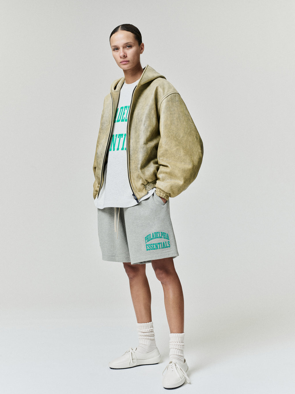 Eagles Merch Tee white graphic T shirt with green collegiate lettering layered under a tan jacket and styled with gray shorts in a studio Tops view