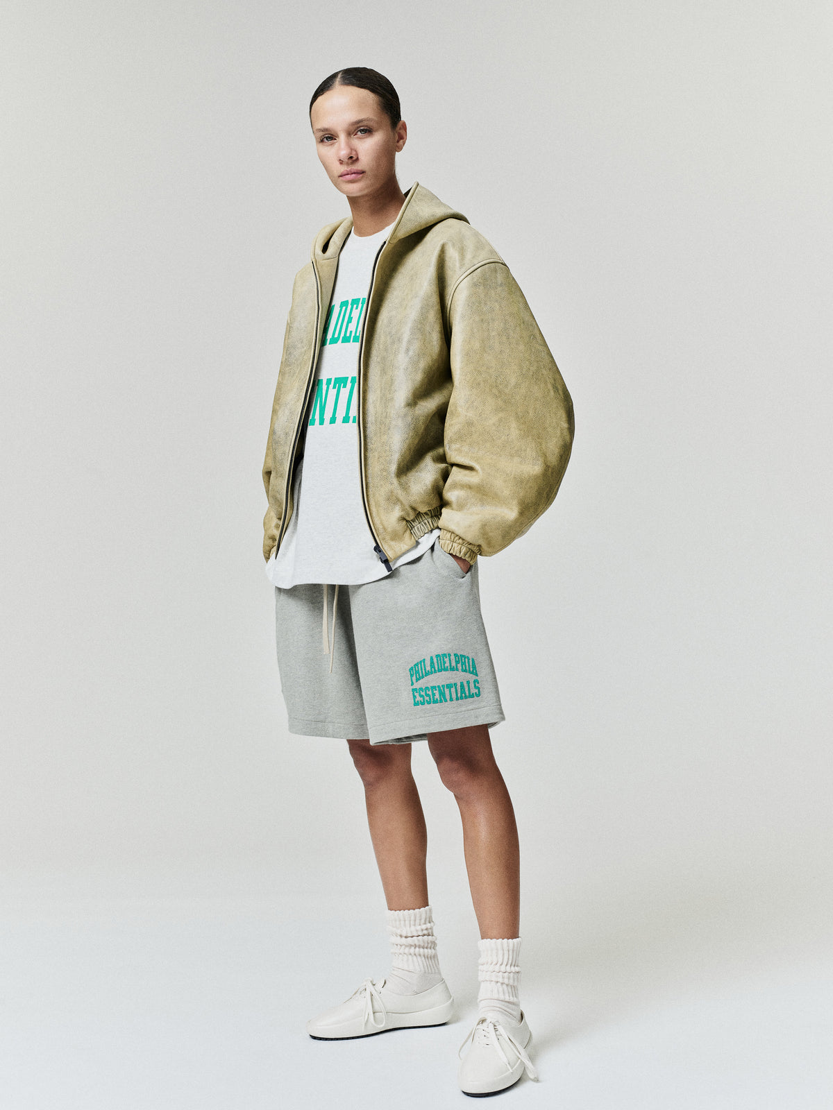 Eagles Merch Tee white graphic T shirt with green collegiate lettering layered under a tan jacket and styled with gray shorts in a studio Tops view