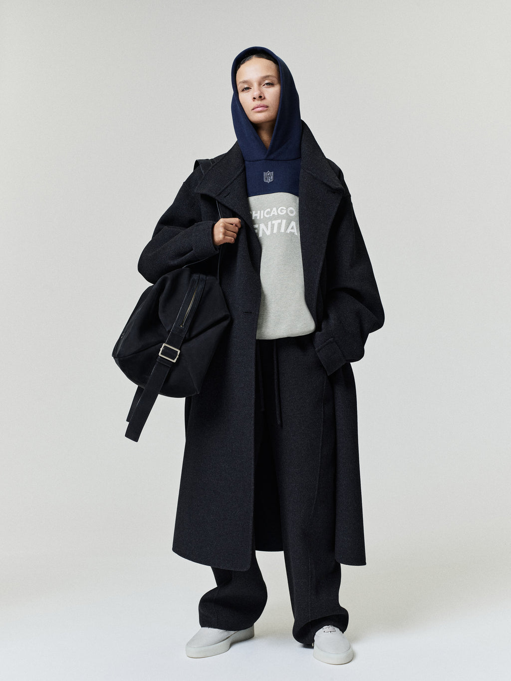 Bears 90s Relaxed Hoodie layered under a black overcoat with black trousers and white sneakers shown on a model as a Tops fashion product view
