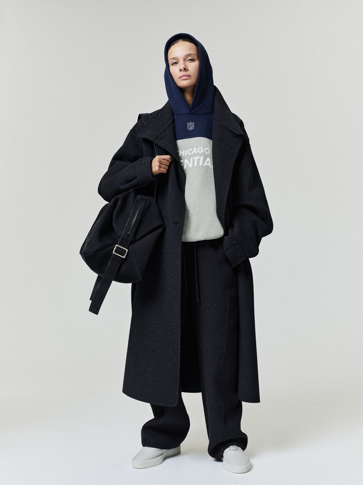 Bears 90s Relaxed Hoodie layered under a black overcoat with black trousers and white sneakers shown on a model as a Tops fashion product view